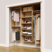 Natural oak 76.5-inch woodgrain Vista Total Closet Kit in a reach-in closet with dresses, shoes, and handbags