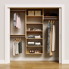 Natural oak 76.5-inch woodgrain Vista Total Closet Kit, front view in a reach-in closet, holding dresses