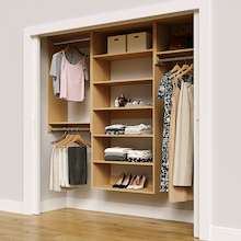 Natural oak 82.5-inch woodgrain Vista Total Closet Kit in a reach-in closet with dresses, shoes, and handbags