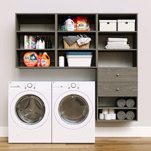 Grey Choice Laundry Kit featuring built-in drawer storage and upper shelves installed above a washer and dryer to organize everyday laundry essentials.