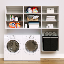 White Select Laundry Kit featuring a built-in pull-out hamper and upper shelves installed above a washer and dryer to organize everyday laundry essentials.