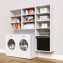 White Select Laundry Kit with a shelf tower with a pull-out hamper and overhead shelving installed above a washer and dryer for organized laundry room storage.
