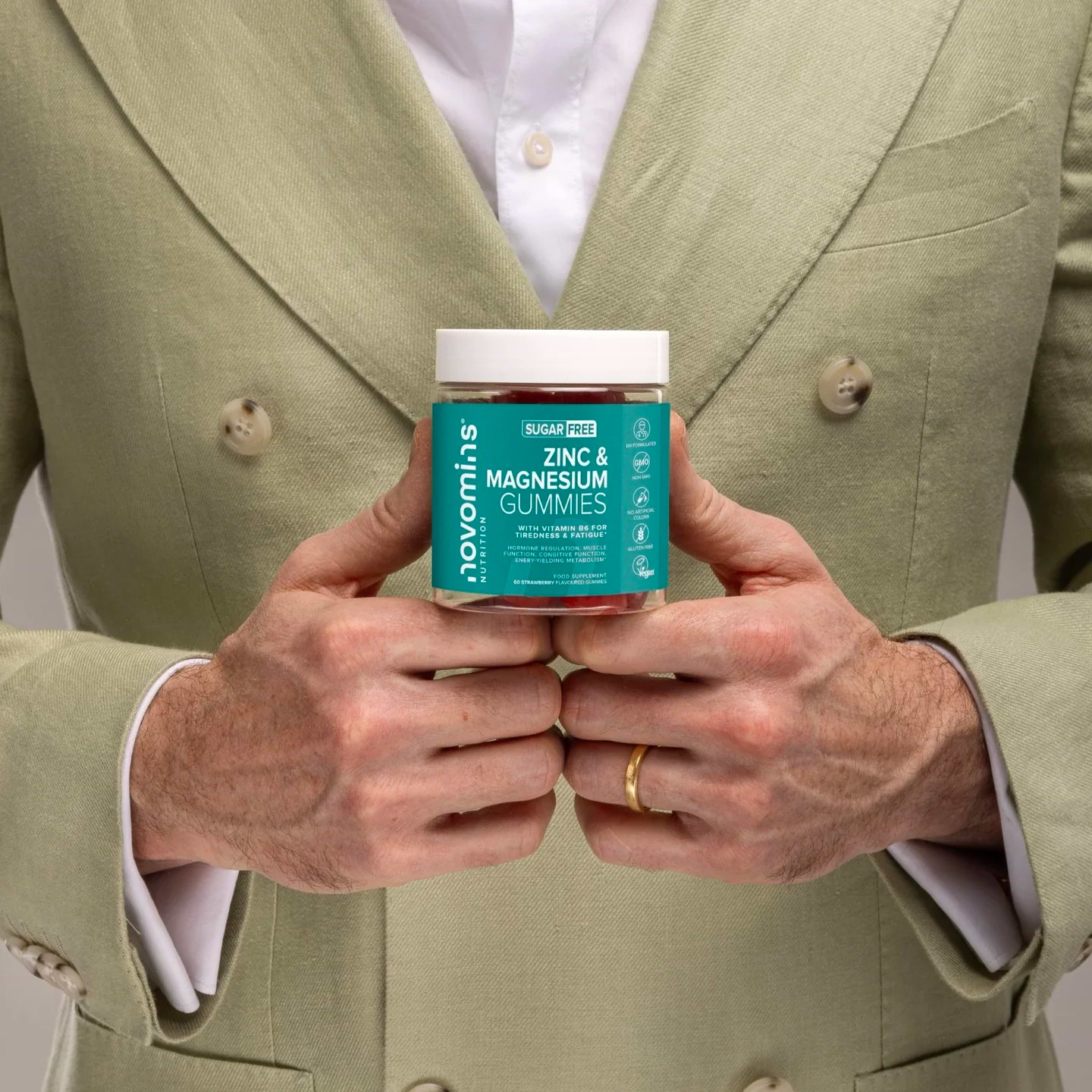 Man in suit holding a bottle of Novomins Zinc & Magnesium gummies