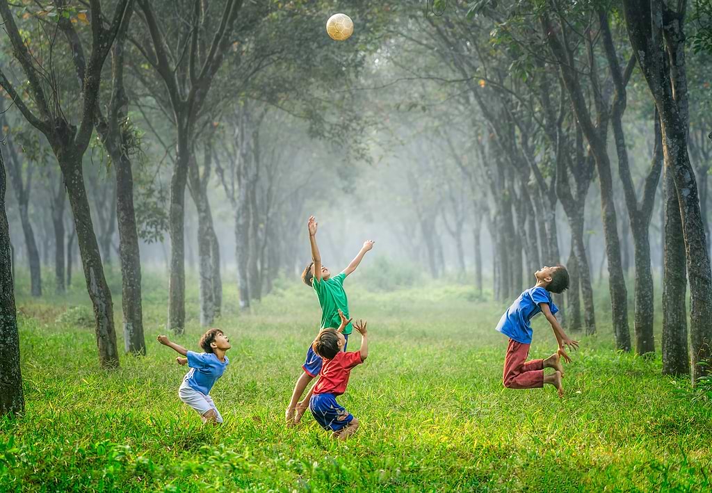 4 Kids playing in a park with a football