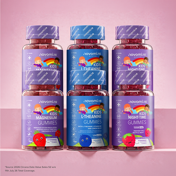 Six bottles of Novomins gummies for kids, arranged in two rows of three on a pink surface against a pink background. The bottles contain red gummies and have purple and blue labels with colorful cartoon illustrations of children.