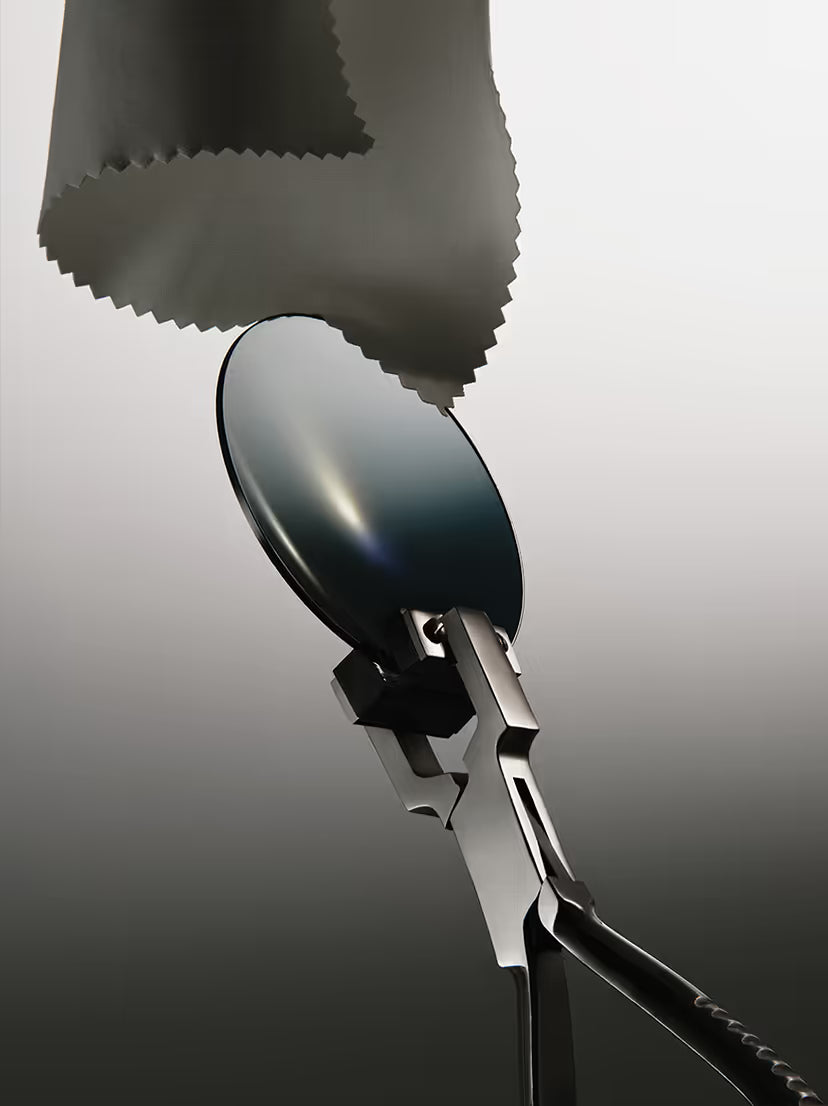 This image features a specialized optical lens cleaning cloth being used to wipe a camera lens or sunglasses.