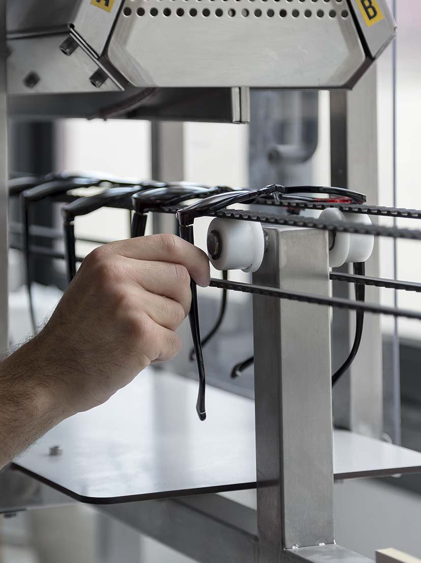 This is an industrial overhead conveyor system used for manufacturing or organizing eyewear.