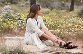 a female model sitting on blanket wearing Jerusalem sandals 