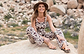 a female model sitting on a rock laughing and wearing Jerusalem sandals