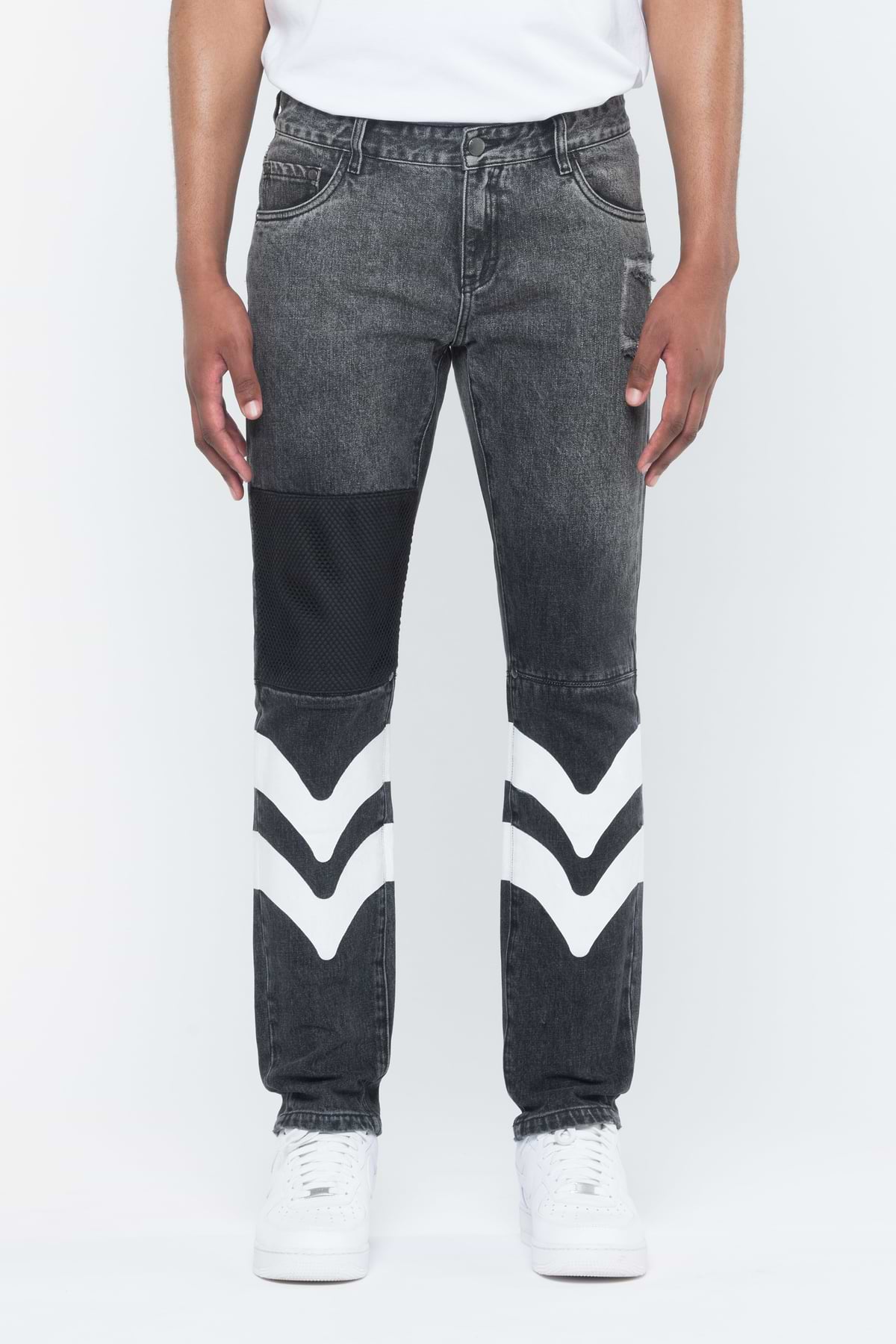 A pair of black denim pants with white leather patches on the leg, viewed from the side.