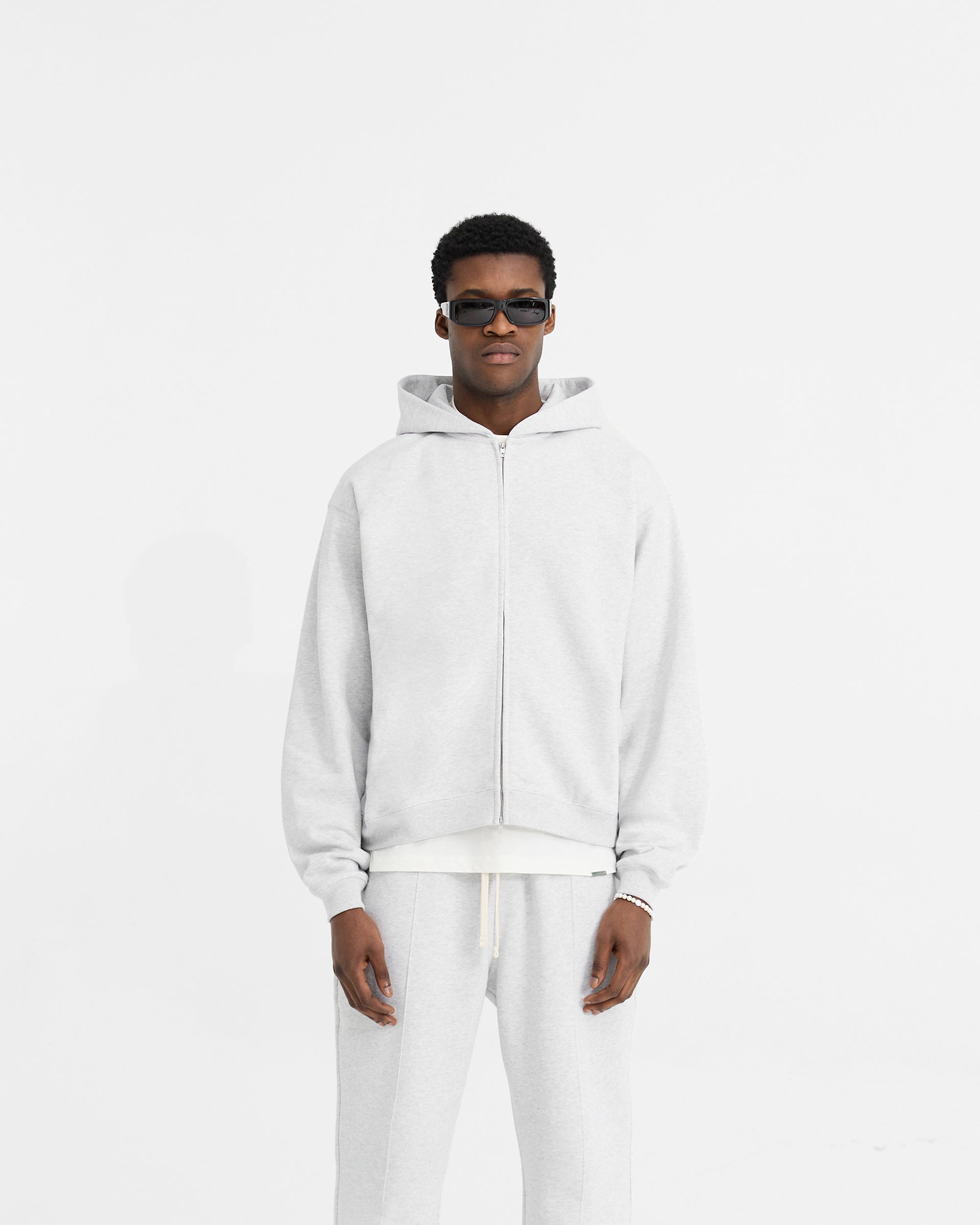 Man wearing an oversized grey zip hoodie on a plain white background | Initial Oversized Zip Hoodie in Ice Grey Marl | Heavyweight loopback jersey with side seam pockets | Initial Hoodies | Represent Clo