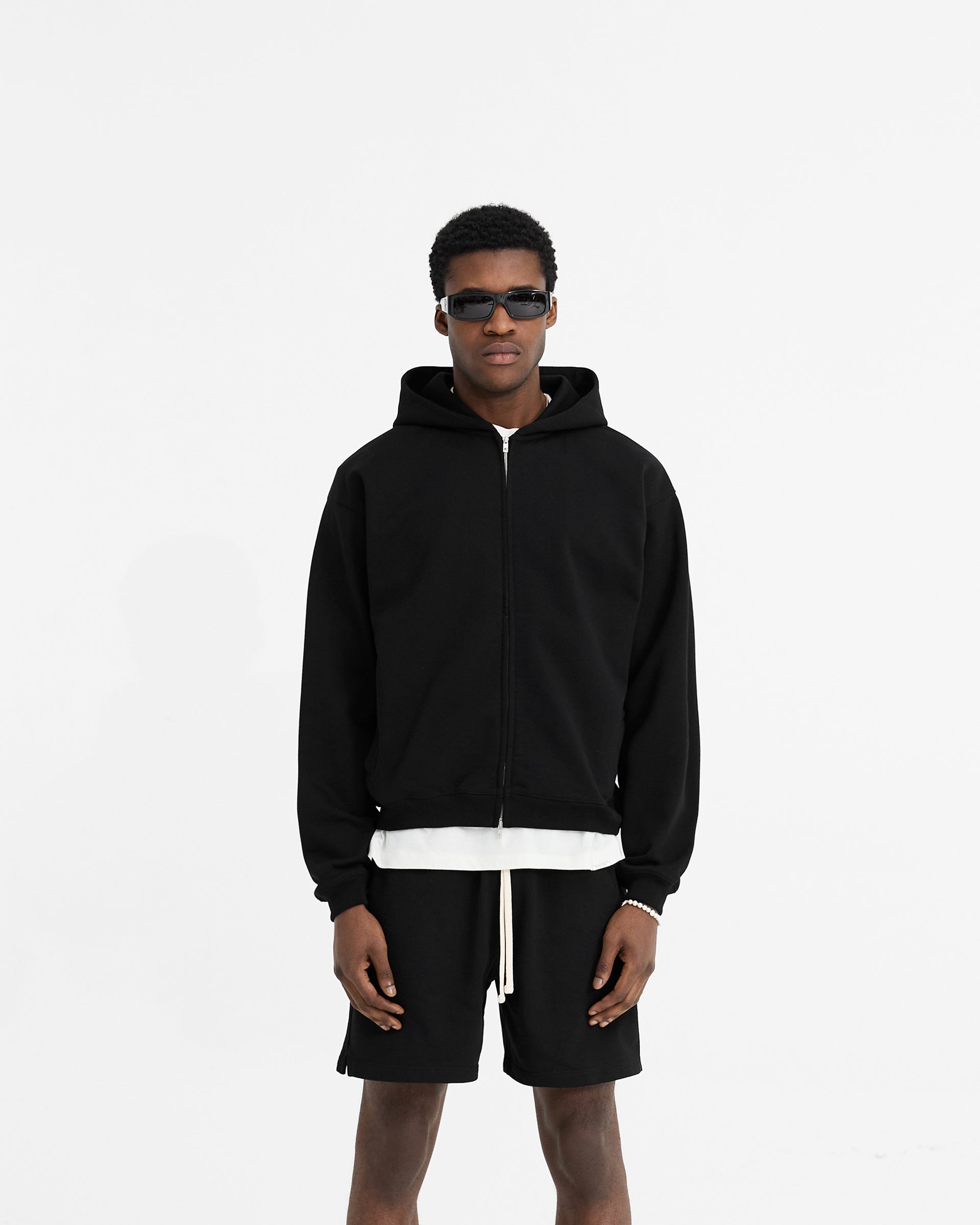 Man wearing a black hoodie on a plain white background | Initial Oversized Zip Hoodie in Black | Loopback jersey cotton hoodie with zip closure | Initial Hoodies | Represent Clo