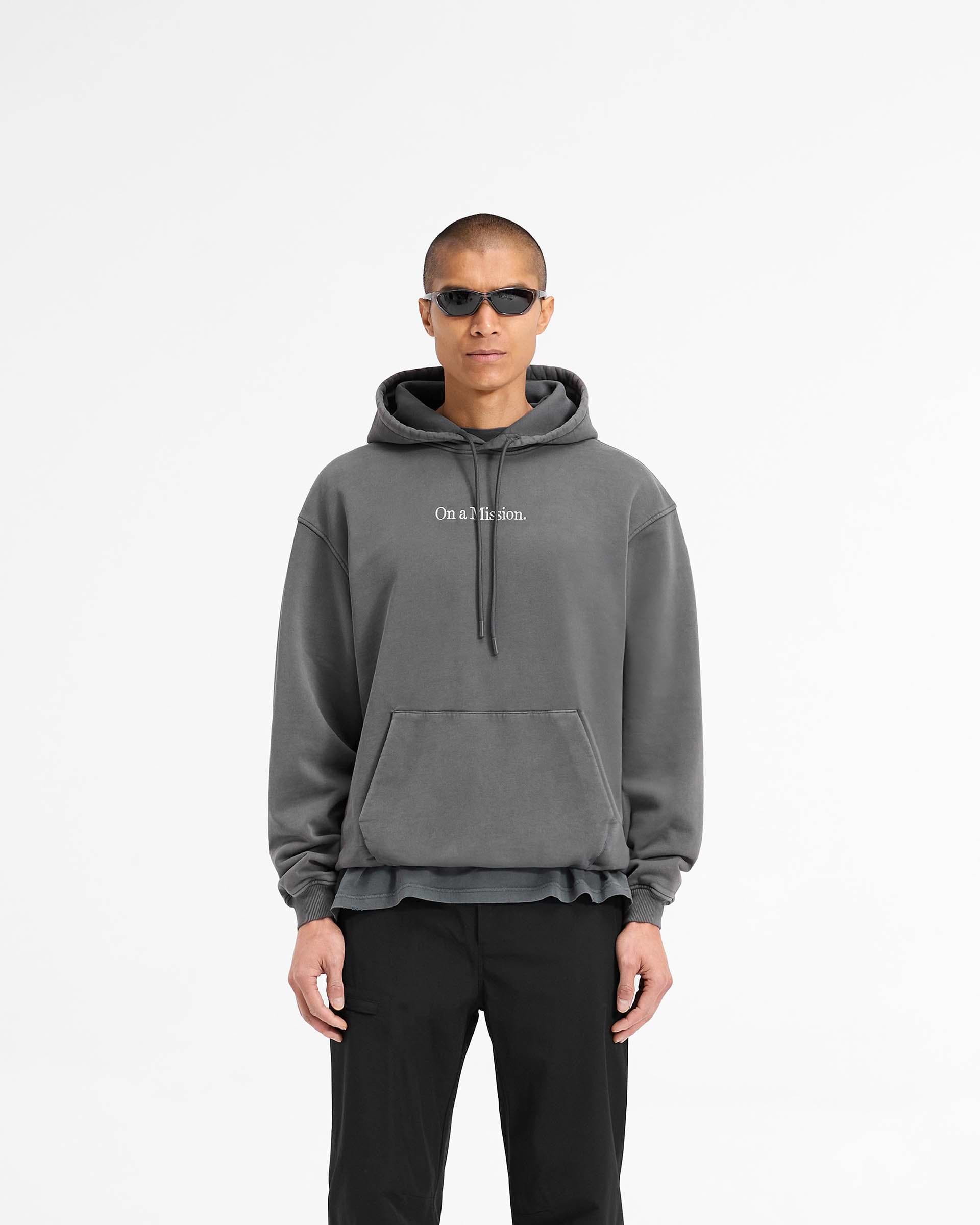 Man wearing a black hoodie on a plain white background | 247 On A Mission Hoodie in Aged Black | Slightly oversized hoodie with embroidery | 247 Hoodies | Represent Clo