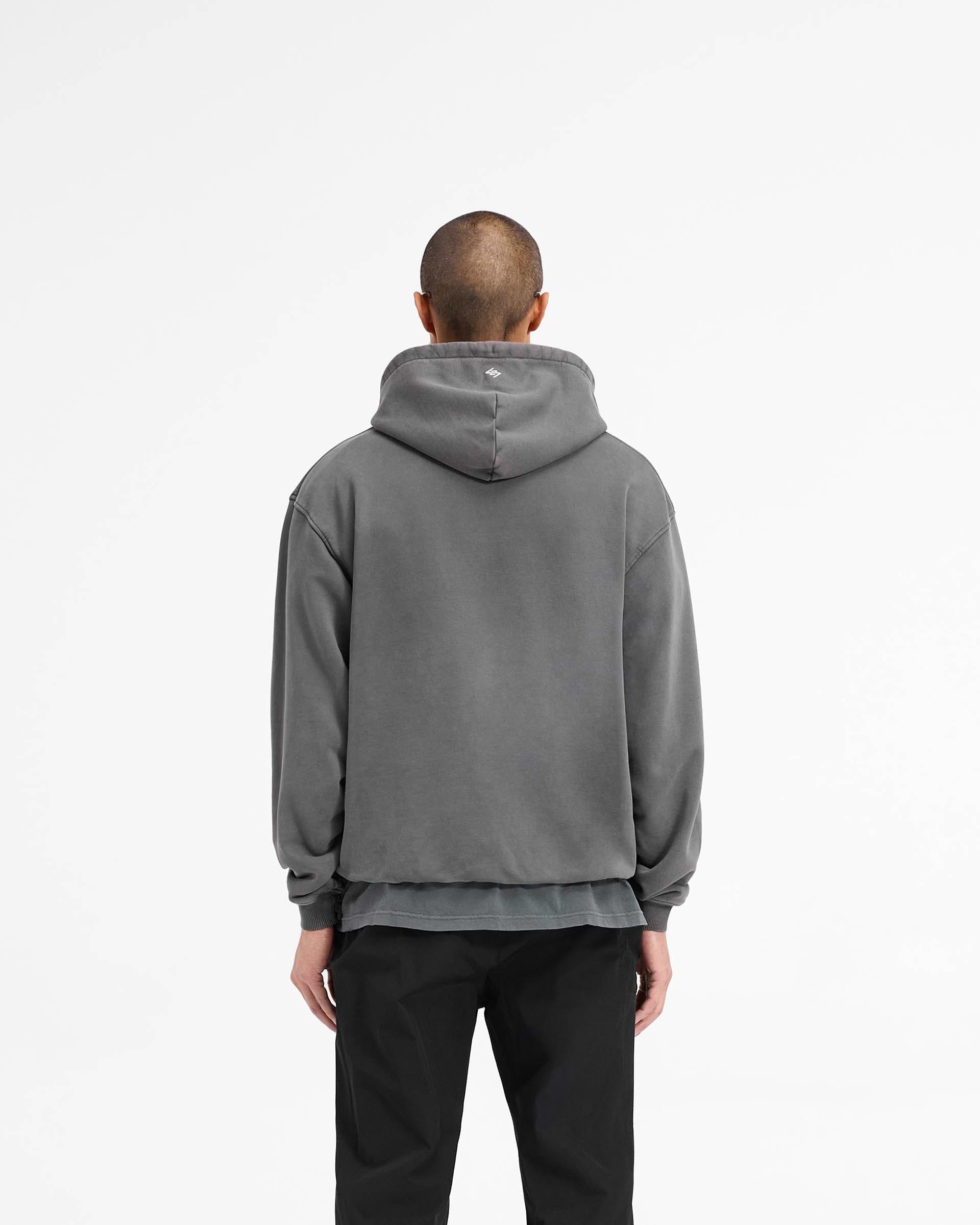 Man wearing a black hoodie on a plain white background | 247 On A Mission Hoodie in Aged Black | Slightly oversized hoodie with embroidery and ribbed trims | 247 Hoodies | Represent Clo
