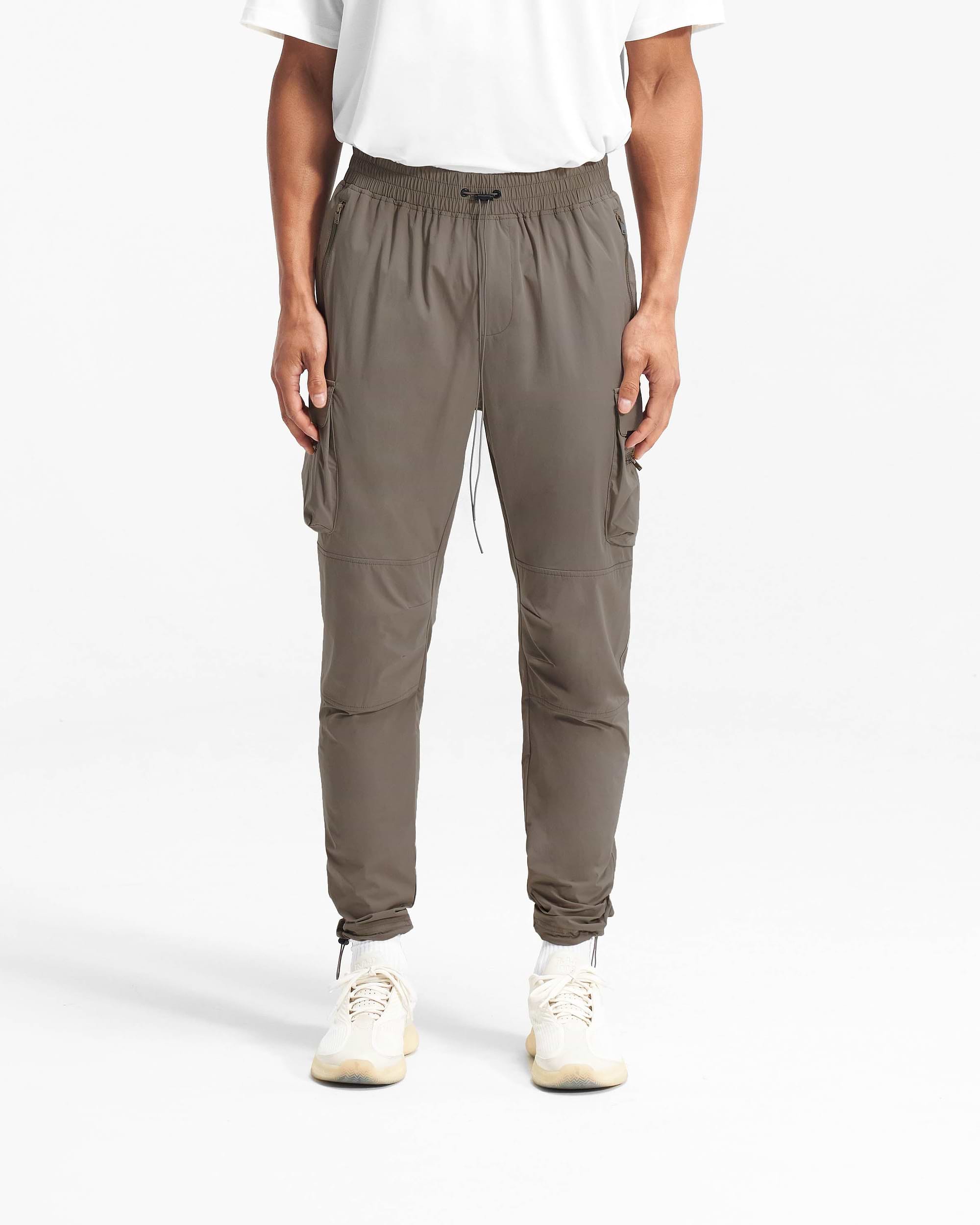 Man wearing olive cargo pants on a plain white background | 247 Pant in Olive | Versatile cargo pants with 4-way stretch and zip side pockets | 247 Pants | Represent Clo