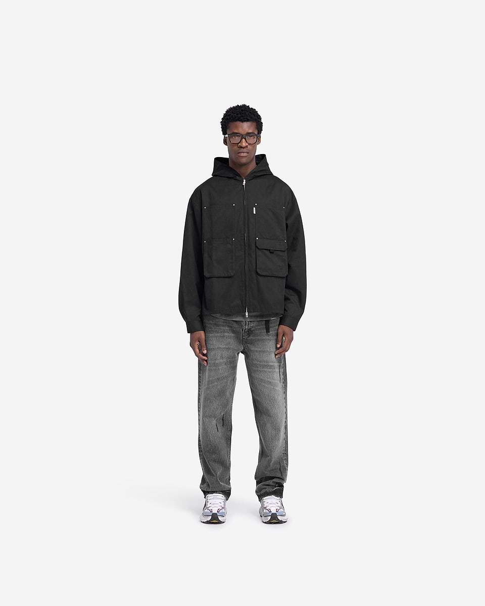 Man wearing a black utility hooded shirt on a plain white background | Utility Hooded Shirt in Jet Black | Hooded shirt with zip closure and multiple pockets | FW24 Shirts | Represent Clo