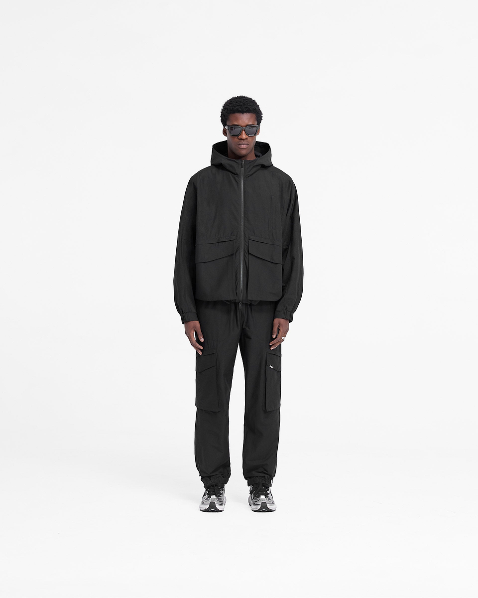 Man wearing a black jacket on a plain white background | Tech Cargo Jacket in Jet Black | Cotton blend jacket with oversized pockets | FW24 Outerwear | Represent Clo