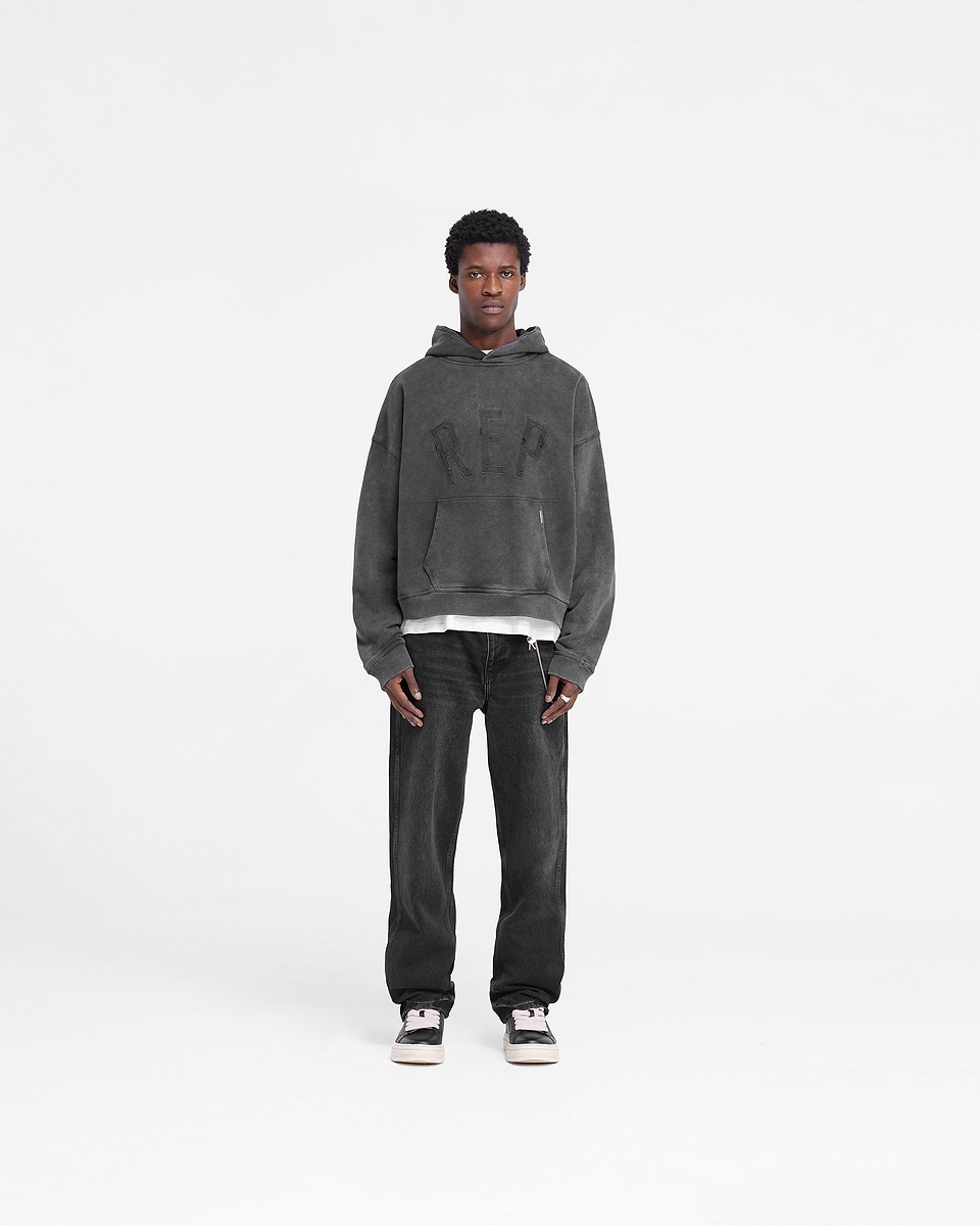 Man wearing an oversized vintage black hoodie on a plain white background | Rep Applique Hoodie in Vintage Black | Boxy fit hoodie with fade out wash | FW24 Hoodies | Represent Clo