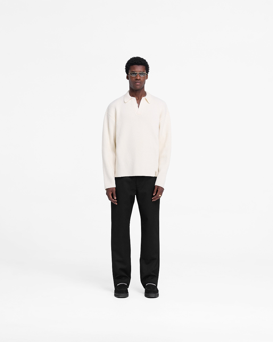 Man wearing an oat ribbed knit polo on a plain white background | Ribbed Knit Polo in Oat | Open neck wool blend polo | FW24 Knitwear | Represent Clo