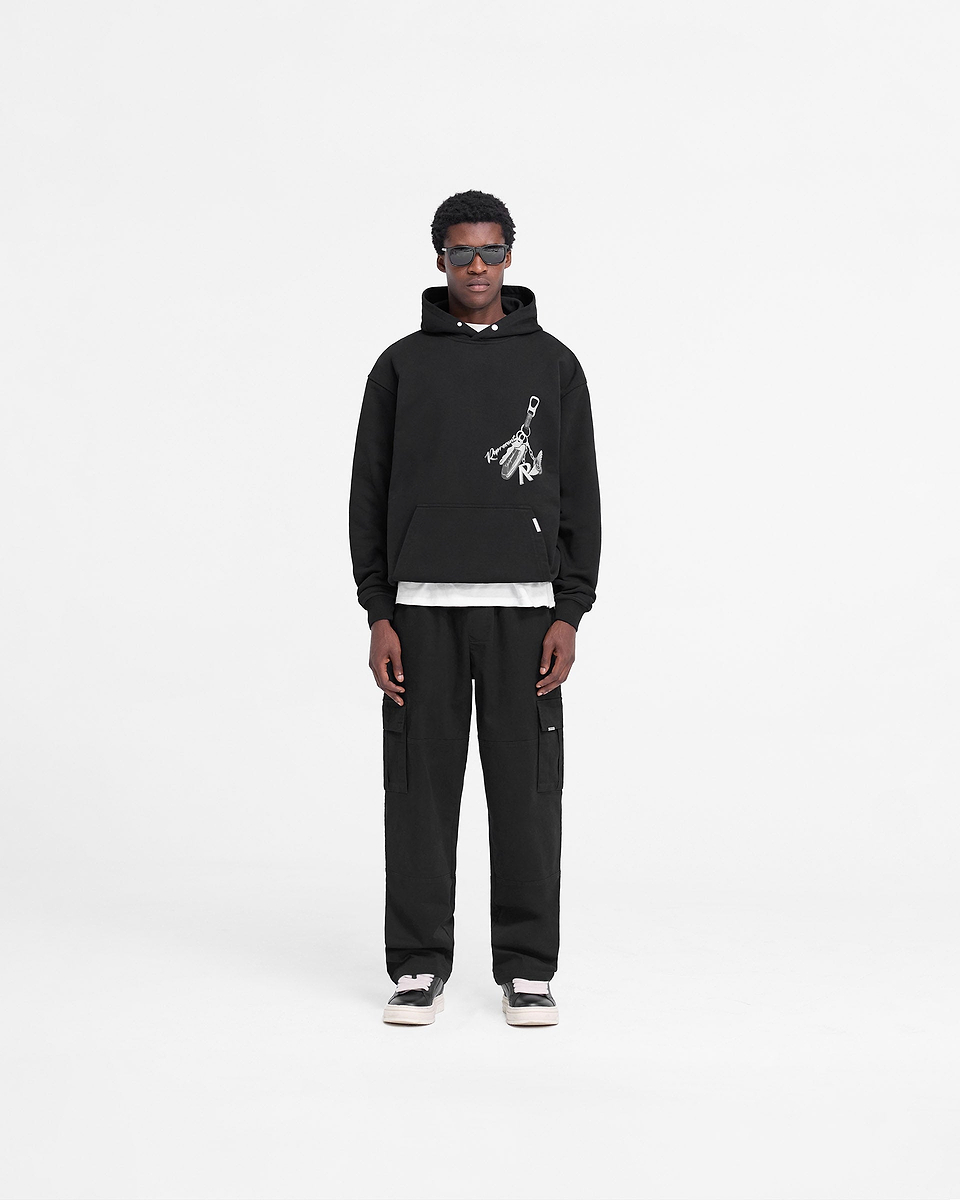 Man wearing a black hoodie on a plain white background | Keys To The Club Hoodie in Jet Black | Slightly oversized hoodie with mixed graphic prints | FW24 Hoodies | Represent Clo