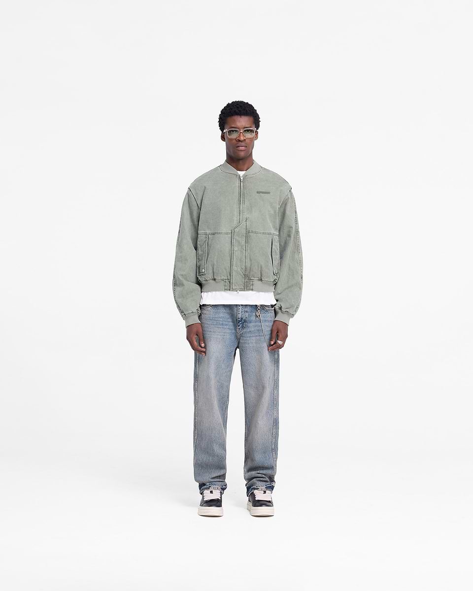 Man wearing a khaki bomber jacket on a plain white background | Inset Sleeve Bomber in Khaki | Cotton bomber with asymmetric placket and shoulder gussets | FW24 Outerwear | Represent Clo