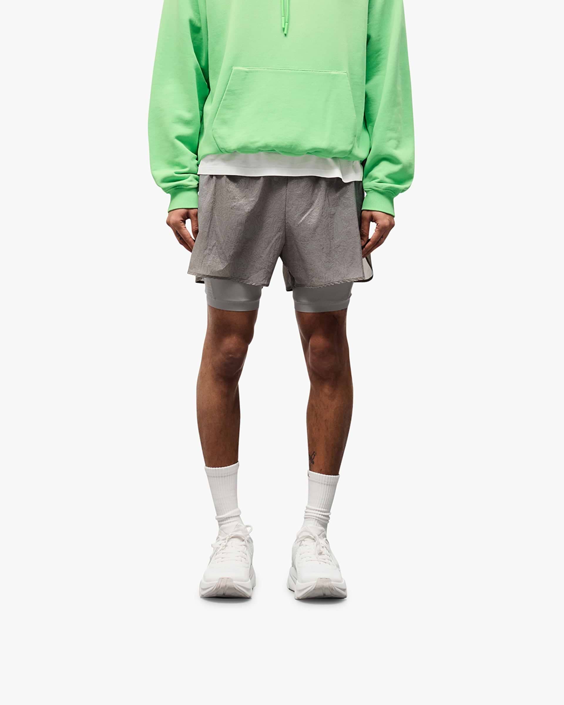 Man wearing grey 2-in-1 run shorts on a plain white background | 247 Contour 2-In-1 Run Shorts in Titanium | Shorts with inner legging and contour print | 247 Shorts | Represent Clo