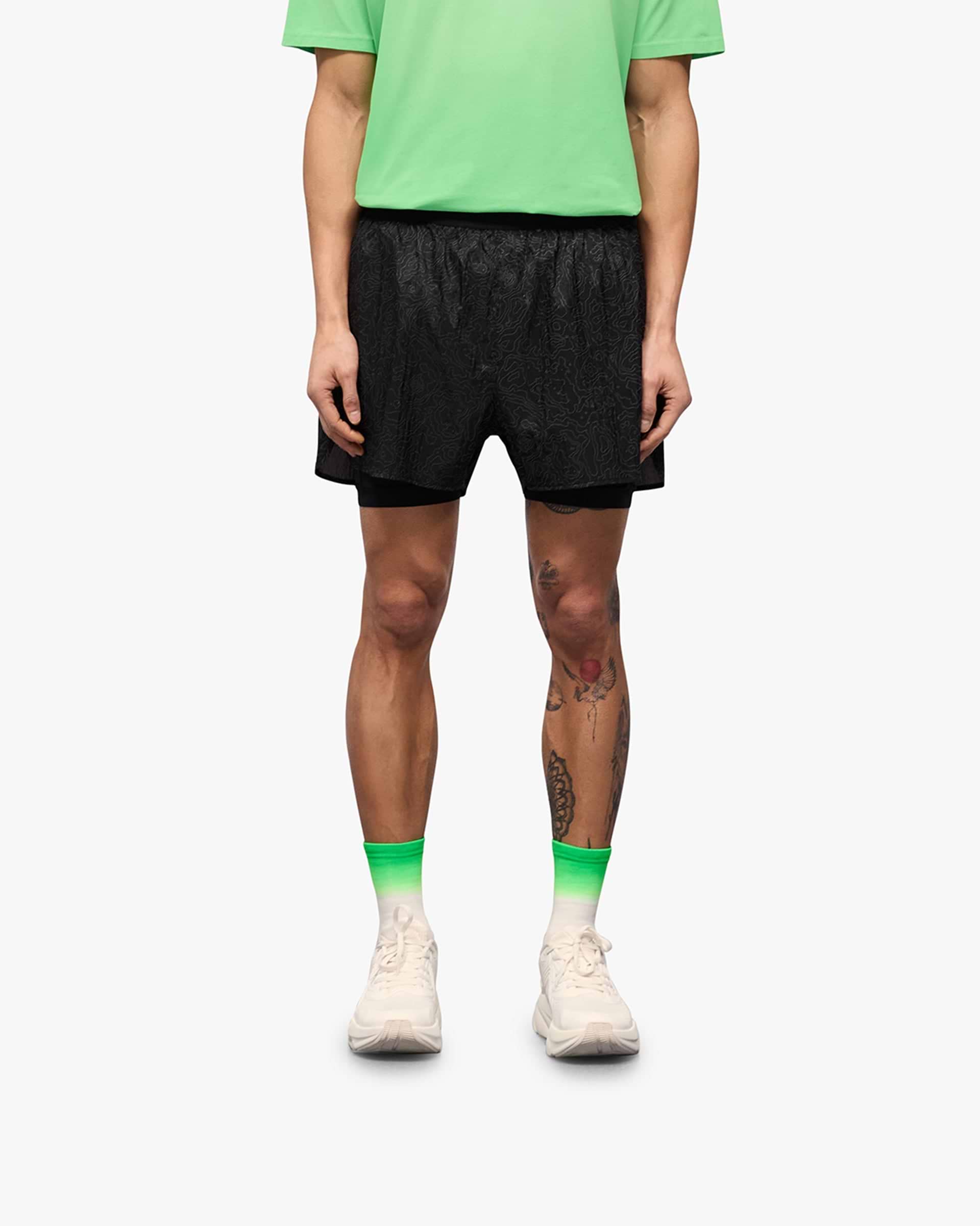 Man wearing black running shorts on a plain white background | 247 Contour 2 In 1 Run Shorts in Black | Running shorts with inner leggings and zip pockets | 247 Shorts | Represent Clo