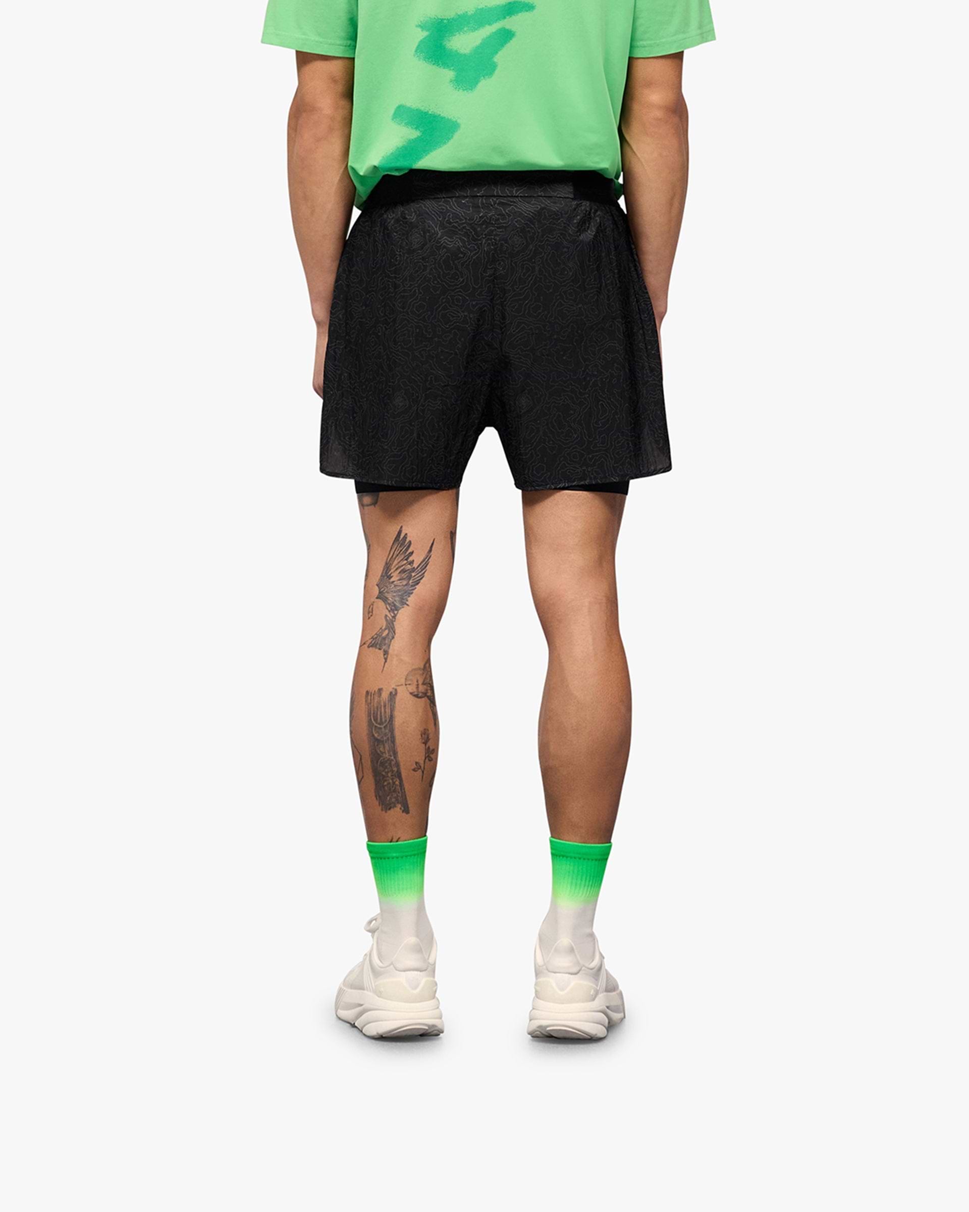 Man wearing black run shorts on a plain white background | 247 Contour 2-In-1 Run Shorts in Black | Shorts with inner legging and zip pockets | 247 Shorts | Represent Clo