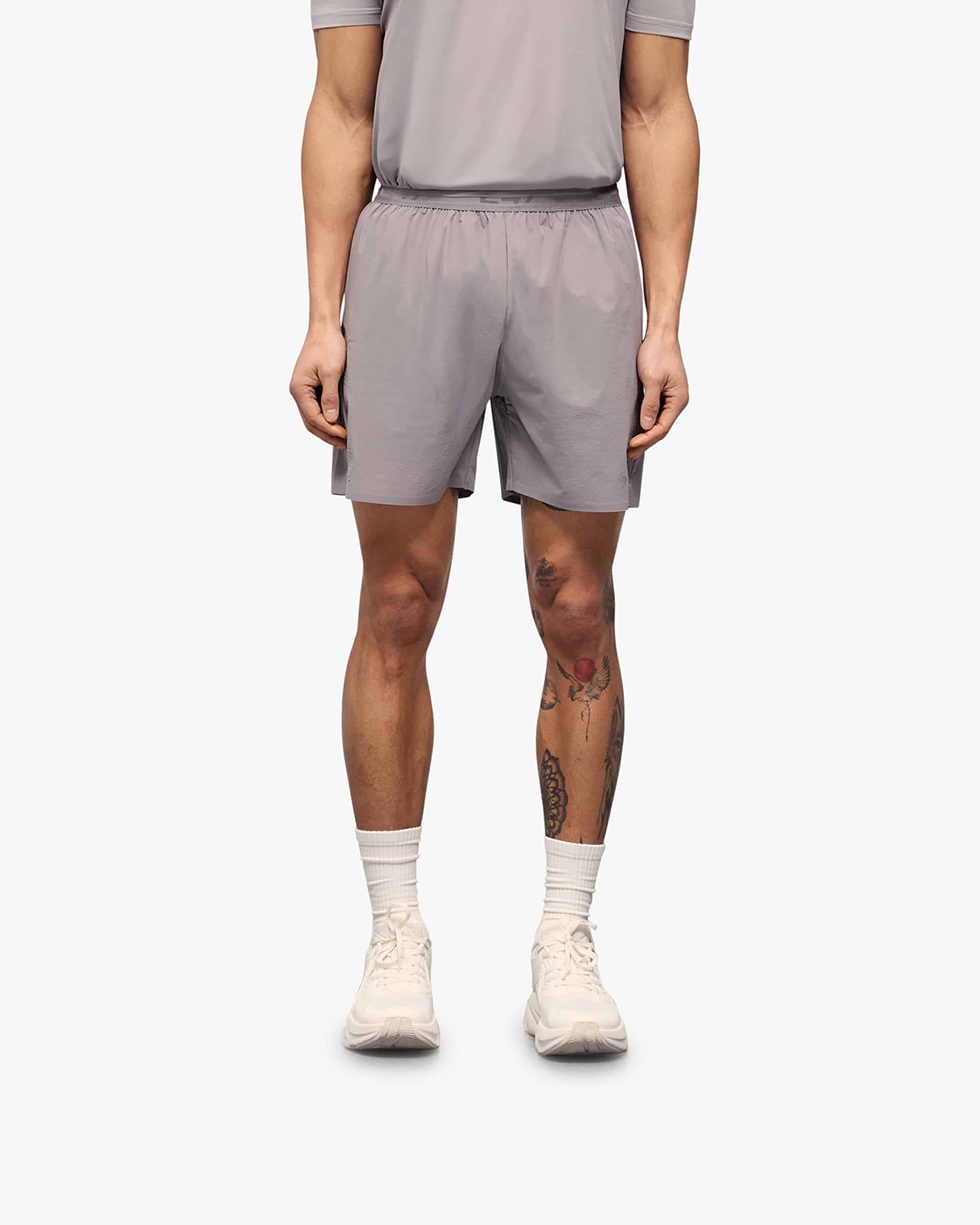 Man wearing grey training shorts on a plain white background | 247 Training Shorts in Titanium | Nylon blend shorts with perforation detailing | 247 Shorts | Represent Clo