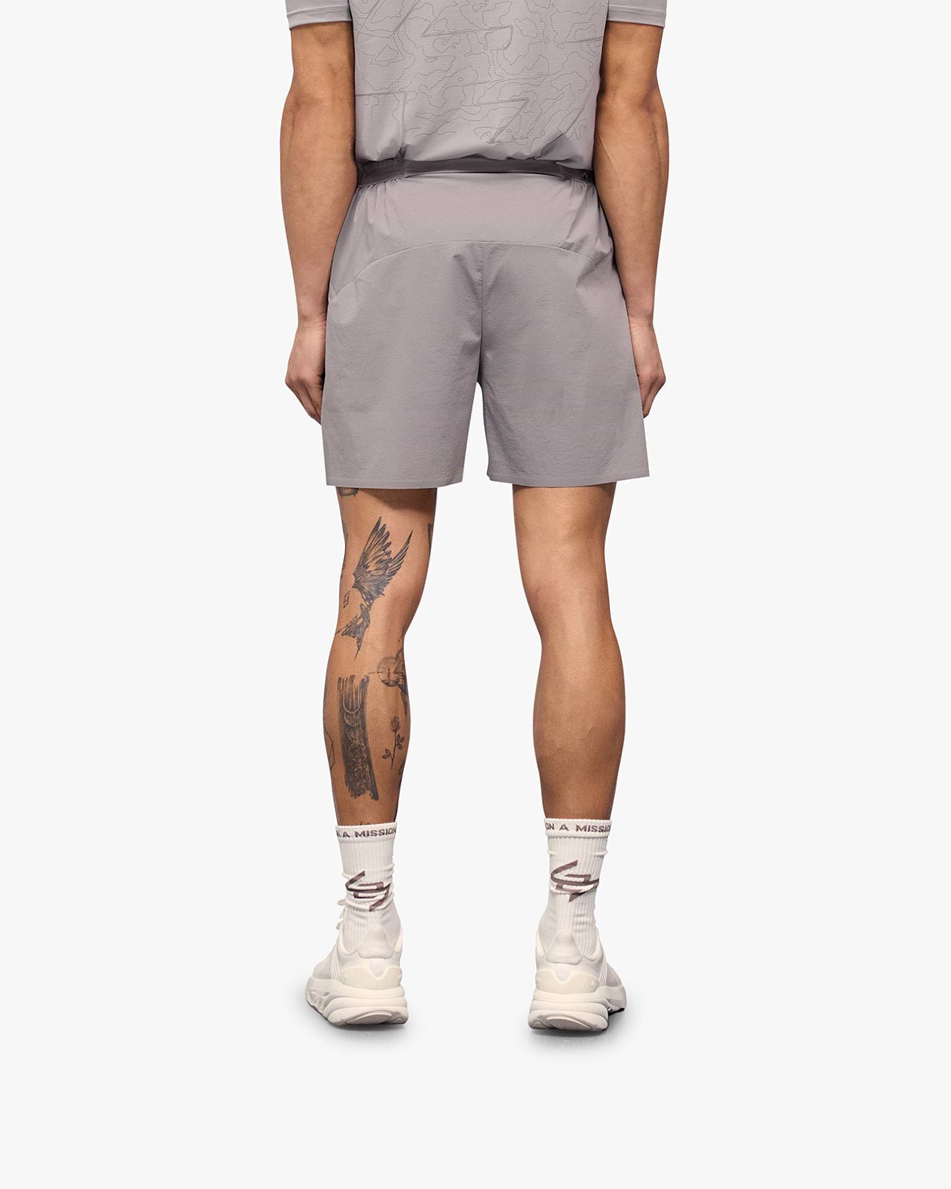 Man wearing grey shorts on a plain white background | 247 Training Shorts in Titanium | Nylon and spandex shorts with perforation detailing | 247 Shorts | Represent Clo
