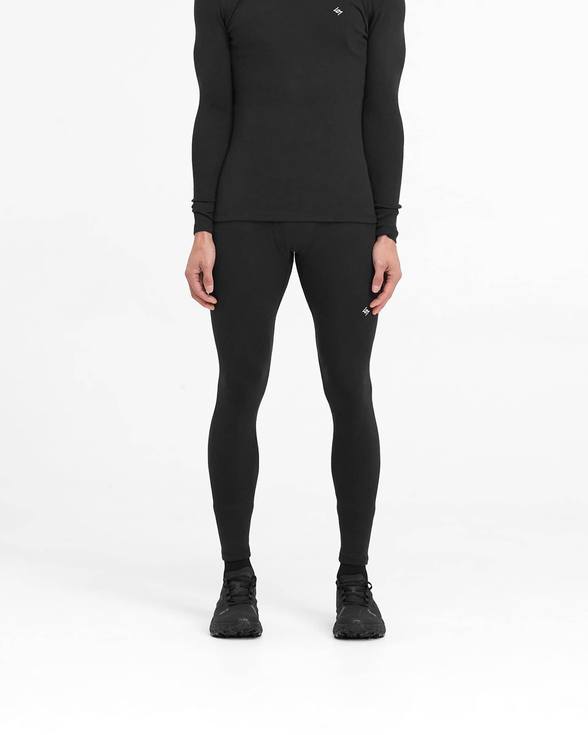 Man wearing black ribbed leggings on a plain white background | 247 Ribbed Legging in Black | Close fit ribbed leggings with embroidered 247 logo | 247 Pants | Represent Clo