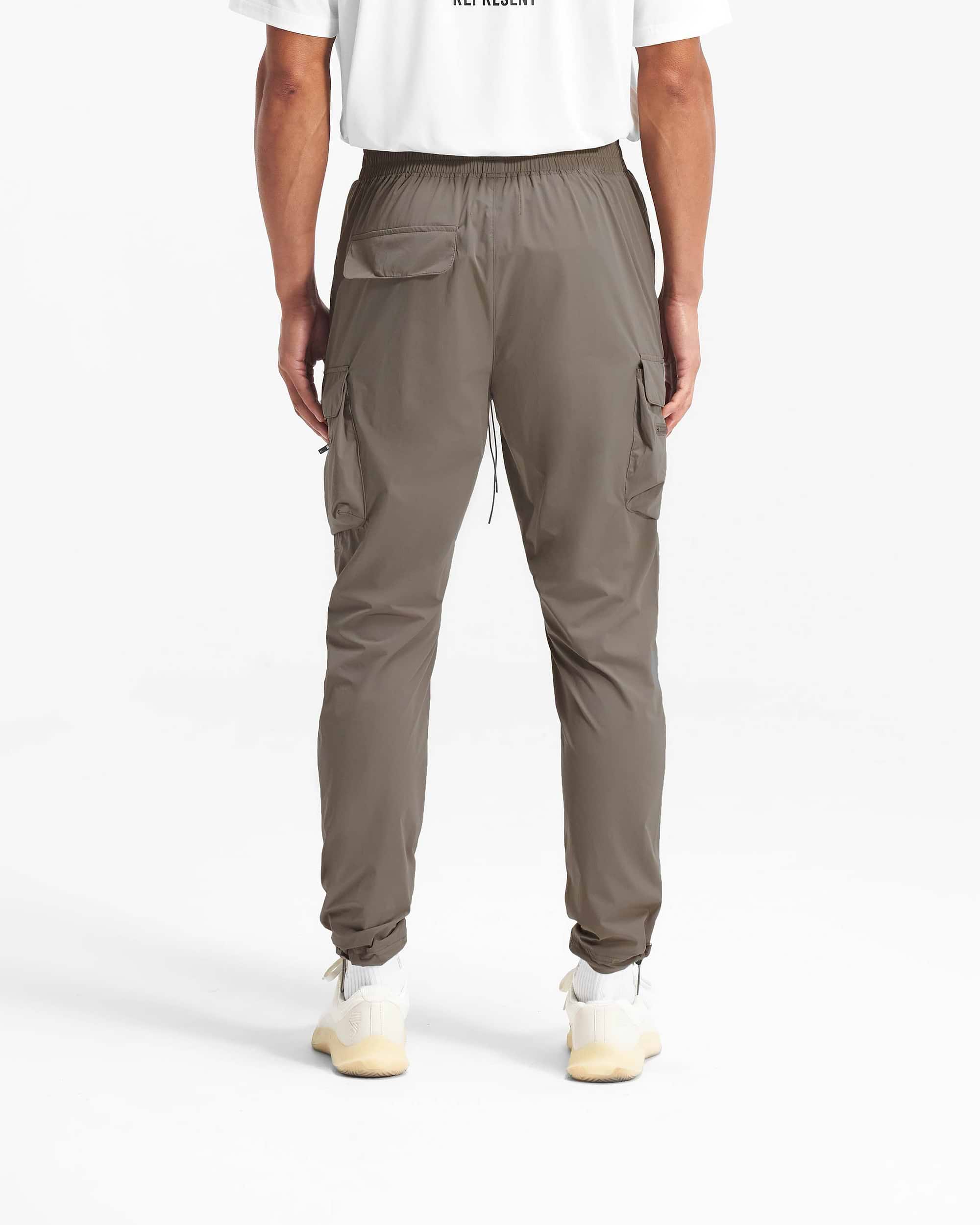 Man wearing olive cargo pants on a plain white background | 247 Pant in Olive | Cargo pants with spacious pockets and adjustable waistband | 247 Pants | Represent Clo