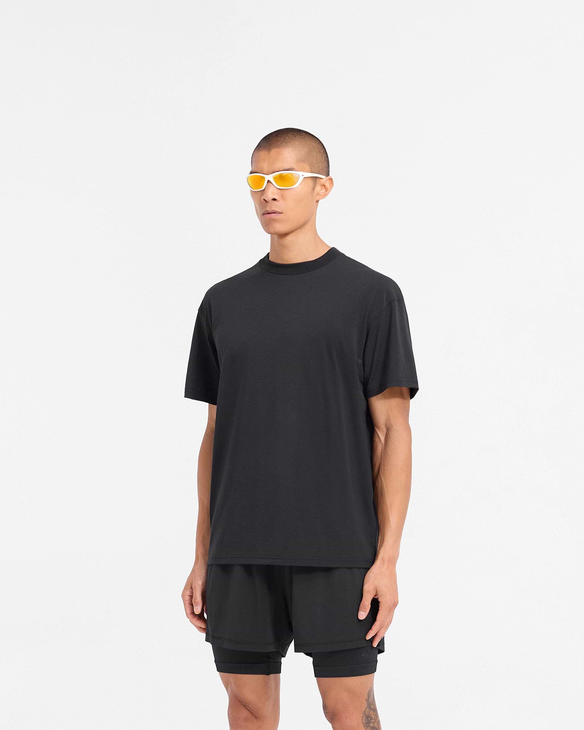 Man wearing a black t-shirt on a plain white background | 247 DNA Oversized T-Shirt in Black | Lightweight gym top with 4-way stretch and oversized fit | 247 T-Shirts | Represent Clo