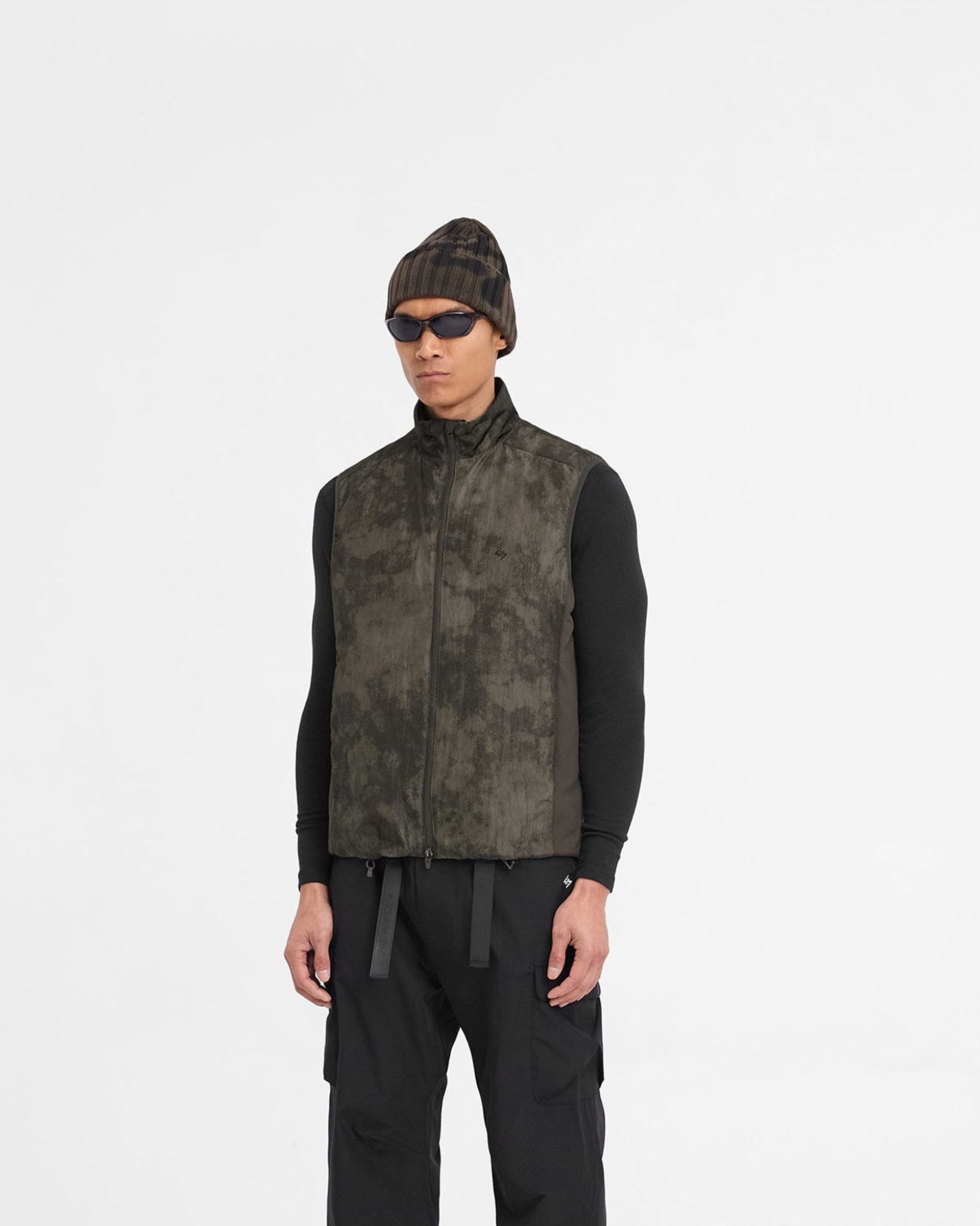 Man wearing a terrain printed gilet on a plain white background | Team 247 Insulated Gilet in Terrain | Insulated gilet with micro ripstop fabric and DWR coating | 247 Outerwear | Represent Clo