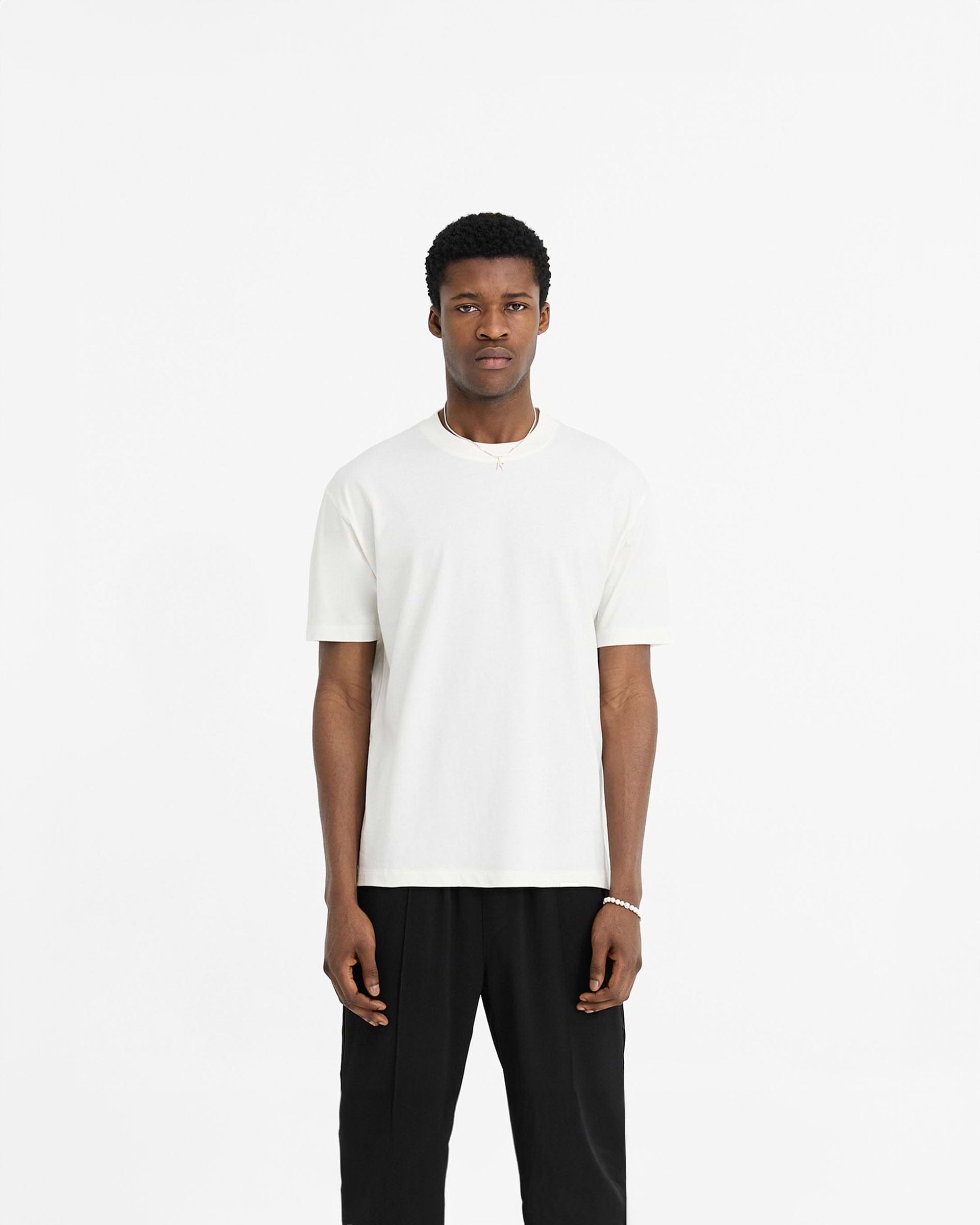 Man wearing a white t-shirt on a plain white background | Initial T-Shirt in Flat White | Slim fit t-shirt with embroidered initial and metal bar logo | Initial T-Shirts | Represent Clo