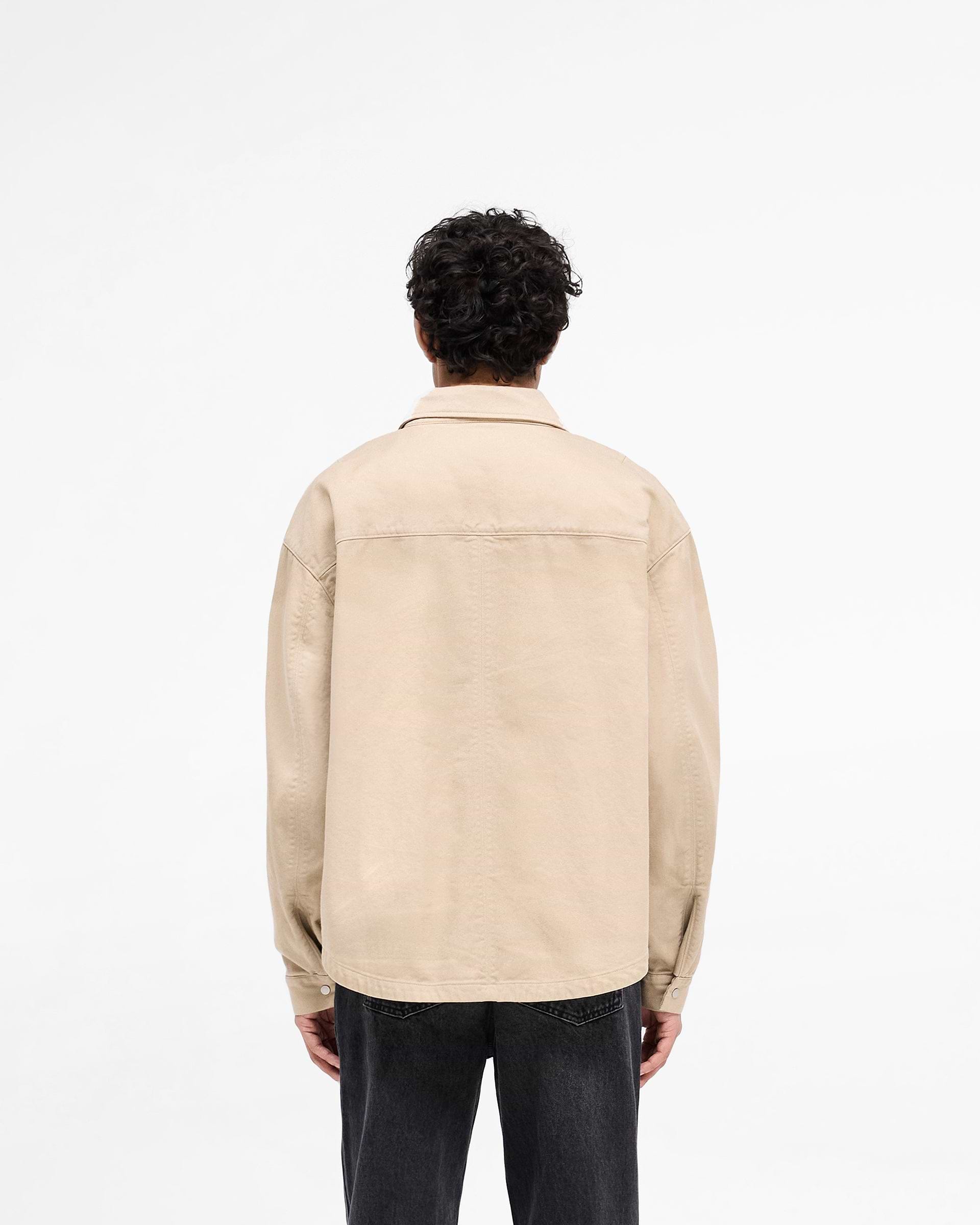 Man wearing a beige cotton shirt on a plain white background | Cotton Zip Through Shirt in Beige | Cotton twill shirt with double zips | SS25 Shirts | Represent Clo