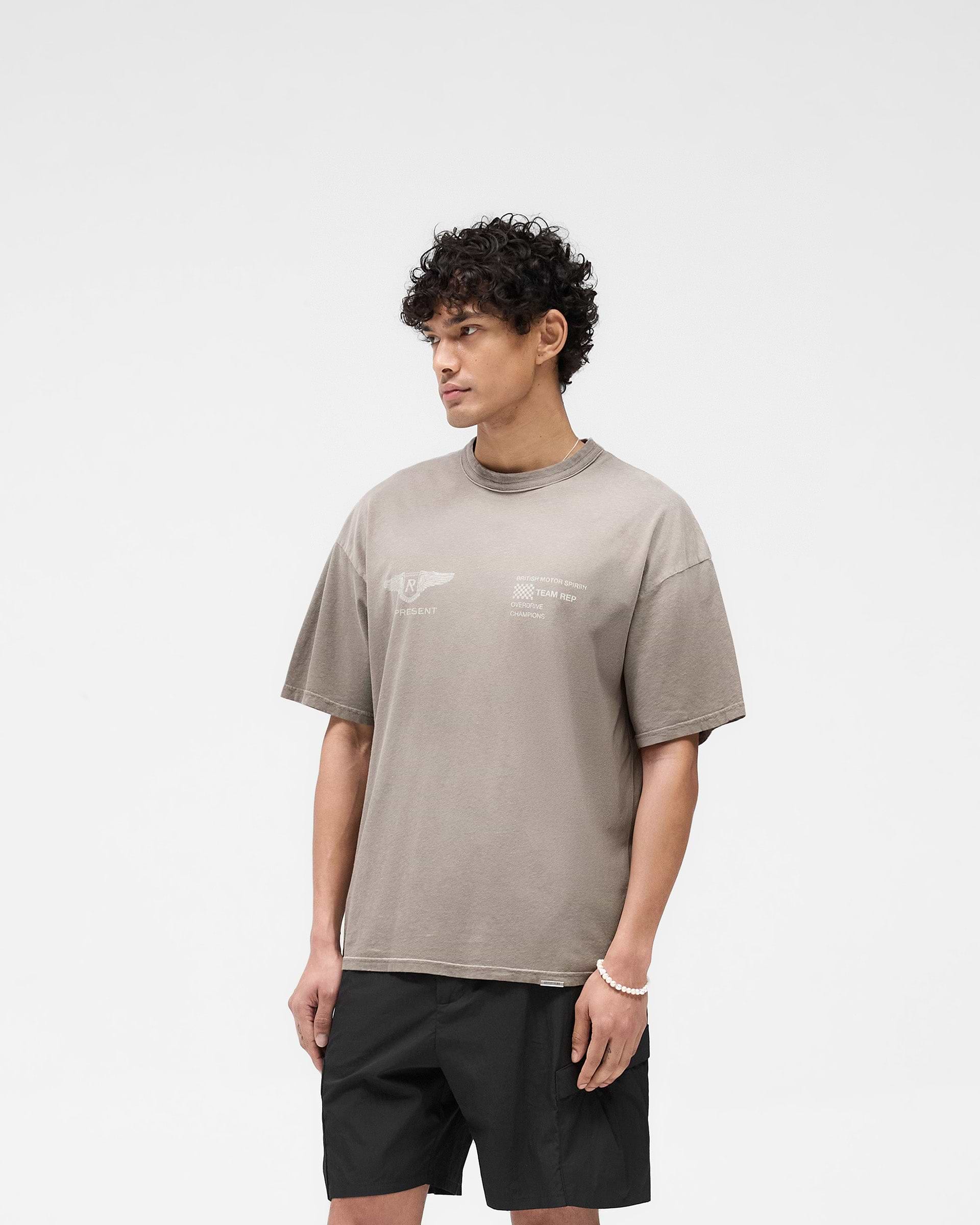 Man wearing a dark taupe t-shirt on a plain white background | Team Rep T-Shirt in Dark Taupe | Oversized slub jersey t-shirt with vintage appeal | SS25 T-Shirts | Represent Clo