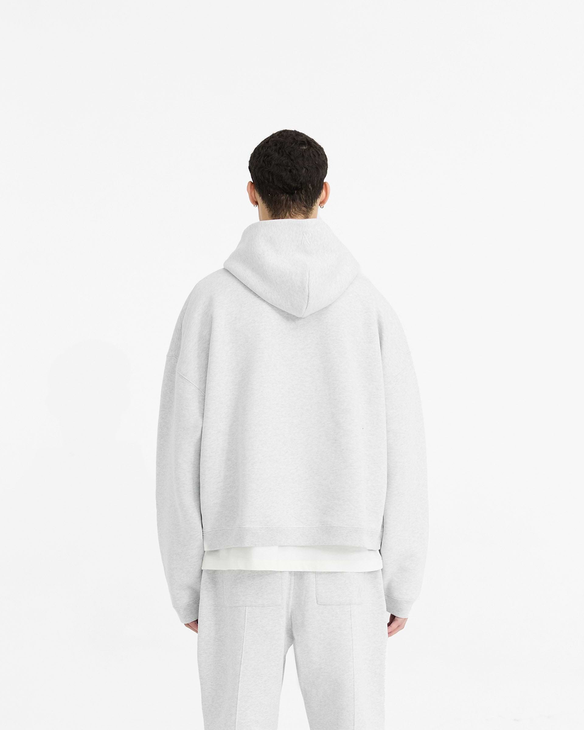 Man wearing an oversized grey hoodie on a plain white background | Initial Boxy Hoodie in Ice Grey Marl | Boxy fit cropped hoodie with ribbed cuffs | Initial Hoodies | Represent Clo
