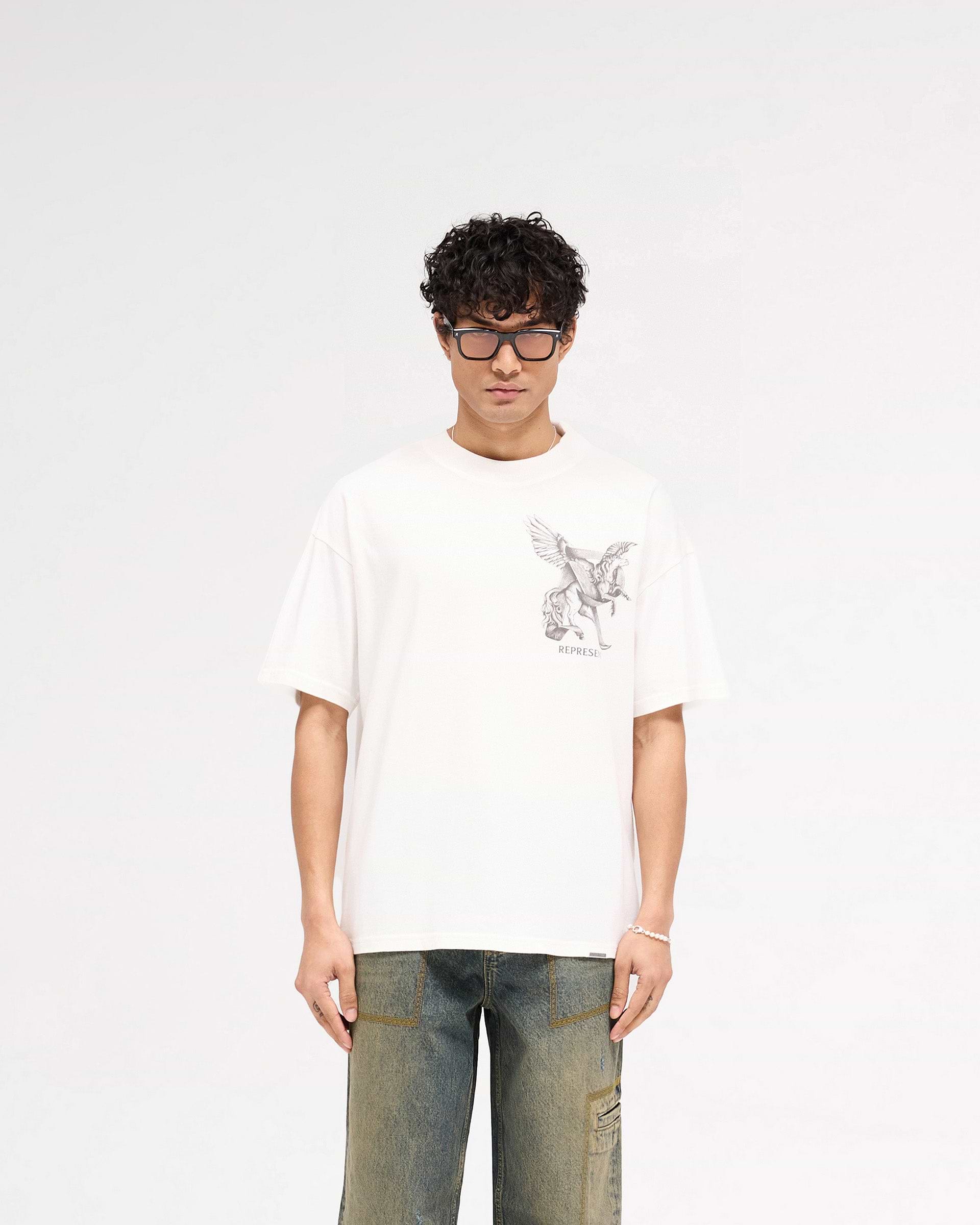 Man wearing a white t-shirt with graphic on a plain white background | Elegance In Motion T-Shirt in Flat White | Slightly oversized fit t-shirt | SS25 T-Shirts | Represent Clo