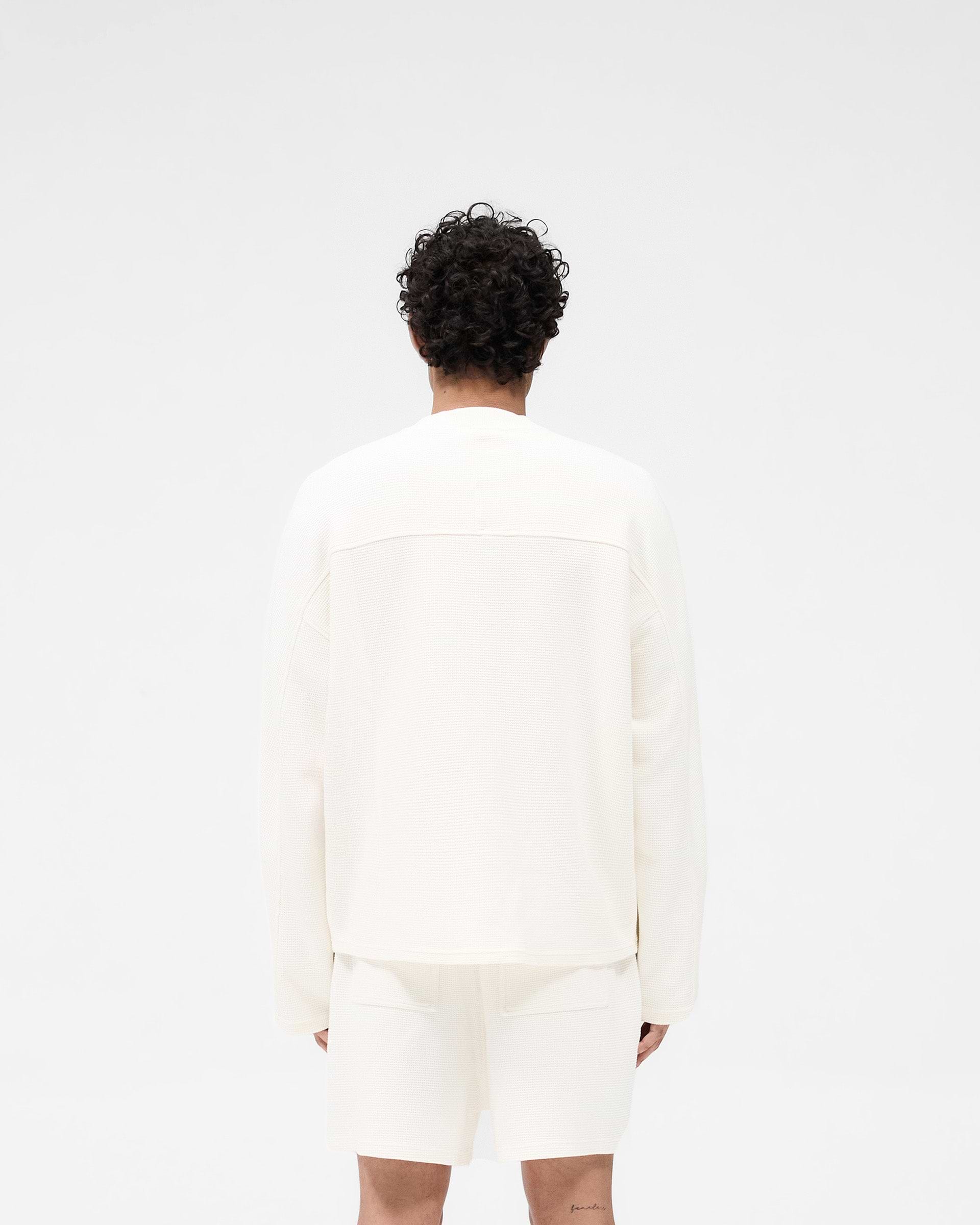 Man wearing a white long sleeve t-shirt on a plain white background | Waffle Long Sleeve T-Shirt in Flat White | Boxy fit t-shirt with interlock waffle fabric | SS25 T-Shirts | Represent Clo