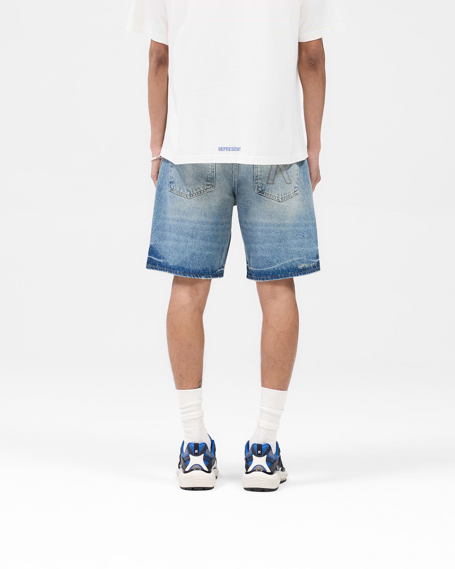Man wearing blue denim shorts on a plain white background | R10T Tailored Denim Shorts in Blue | Structured mid-length premium rigid denim shorts | SS25 Denim | Represent Clo