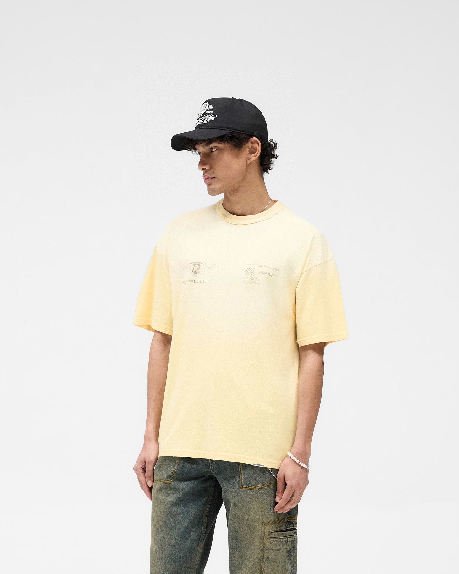 Man wearing a yellow t-shirt on a plain white background | Team Rep T-Shirt in Light Yellow | Slub jersey oversized t-shirt with vintage appeal | SS25 T-Shirts | Represent Clo