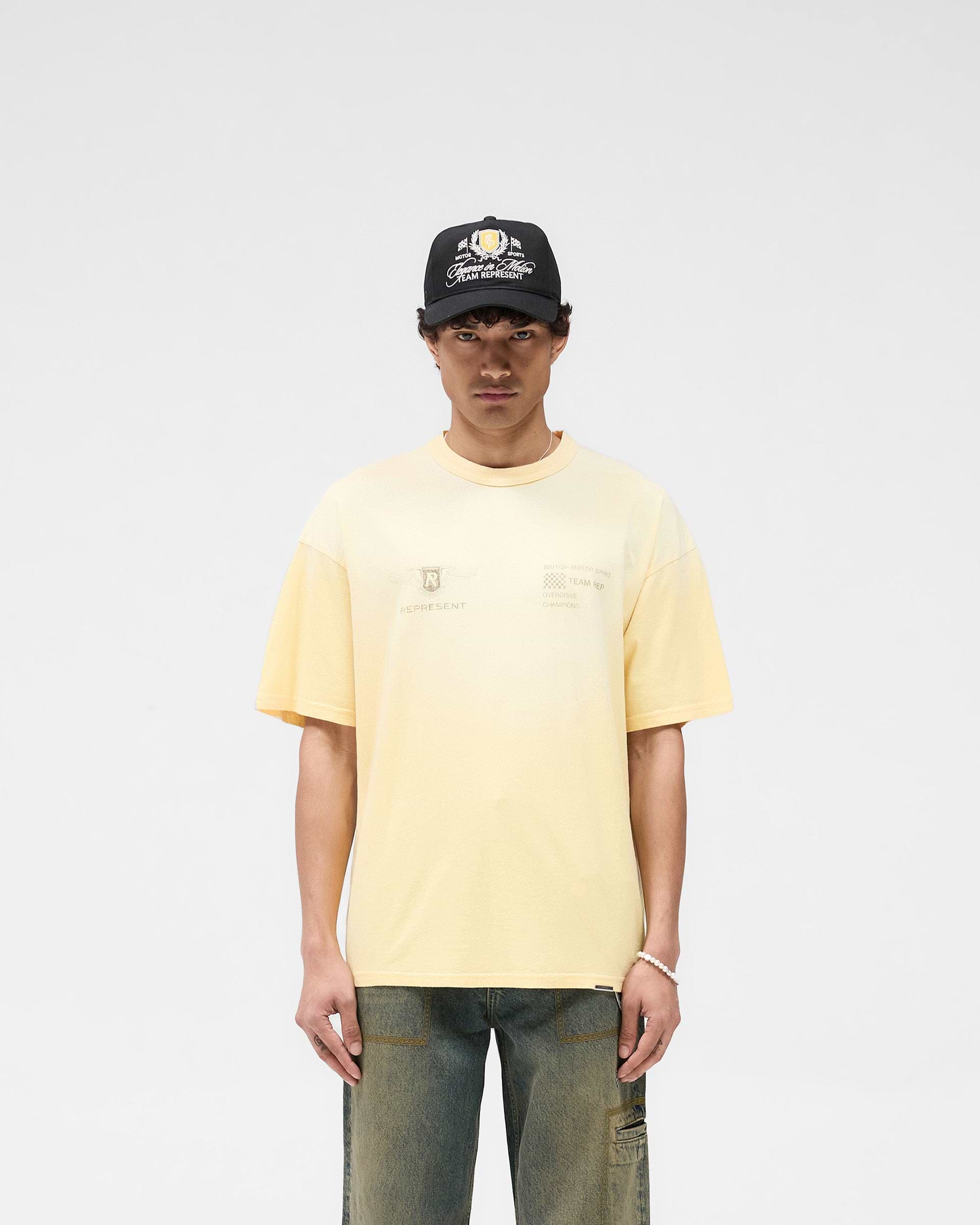 Man wearing a light yellow t-shirt on a plain white background | Team Rep T-Shirt in Light Yellow | Oversized slub jersey t-shirt with spray effect | SS25 T-Shirts | Represent Clo