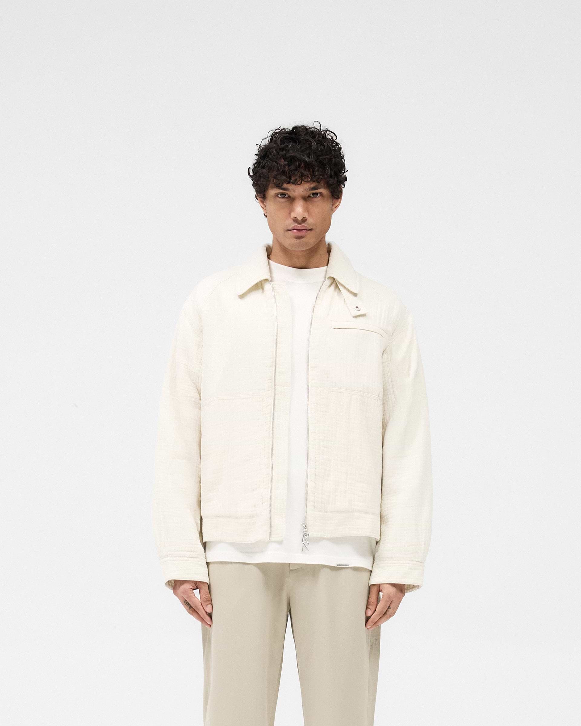Man wearing an ecru jacket on a plain white background | Crinkle Trucker Jacket in Ecru | Lightweight cotton jacket with oversized fit | SS25 Outerwear | Represent Clo