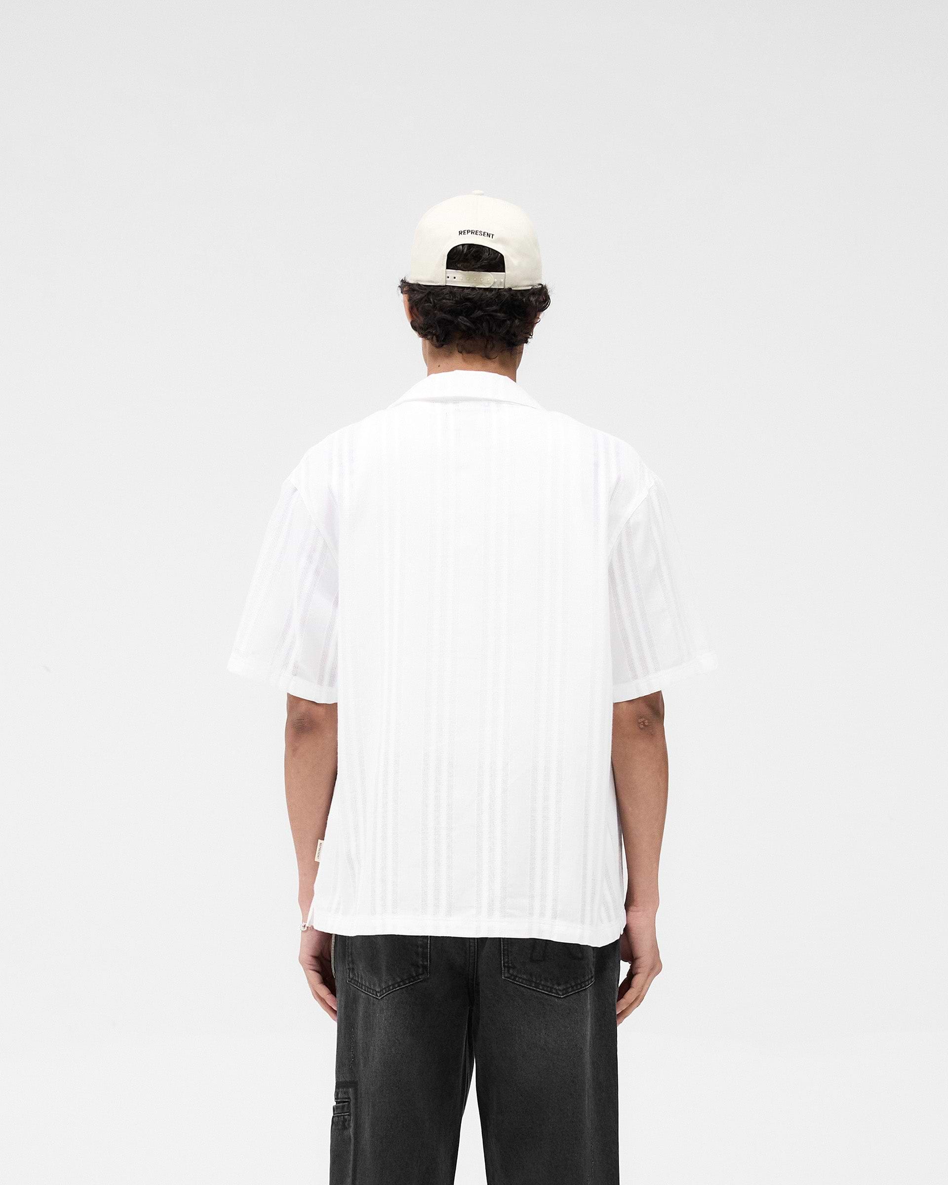 Man wearing a white embroidered bowling shirt on a plain white background | Embroidered Bowling Shirt in Antique White | Lightweight relaxed fit bowling shirt | SS25 Shirts | Represent Clo