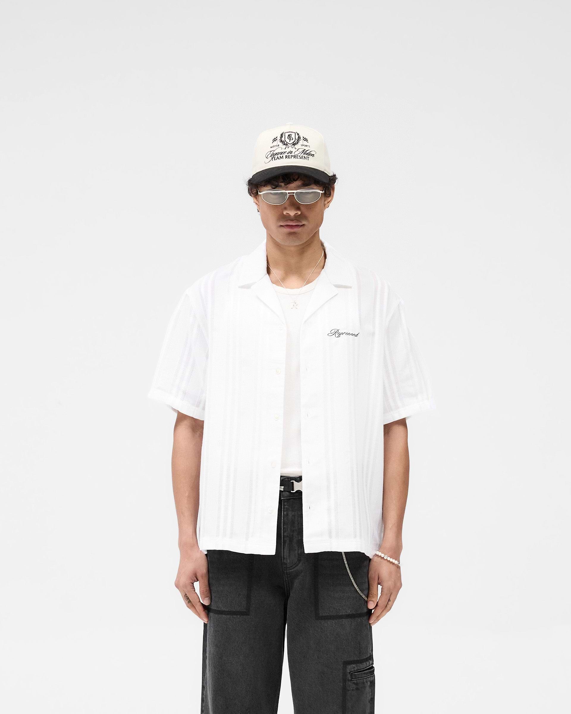Man wearing an antique white shirt on a plain white background | Embroidered Bowling Shirt in Antique White | Sheer fabric with panelled detailing | SS25 Shirts | Represent Clo