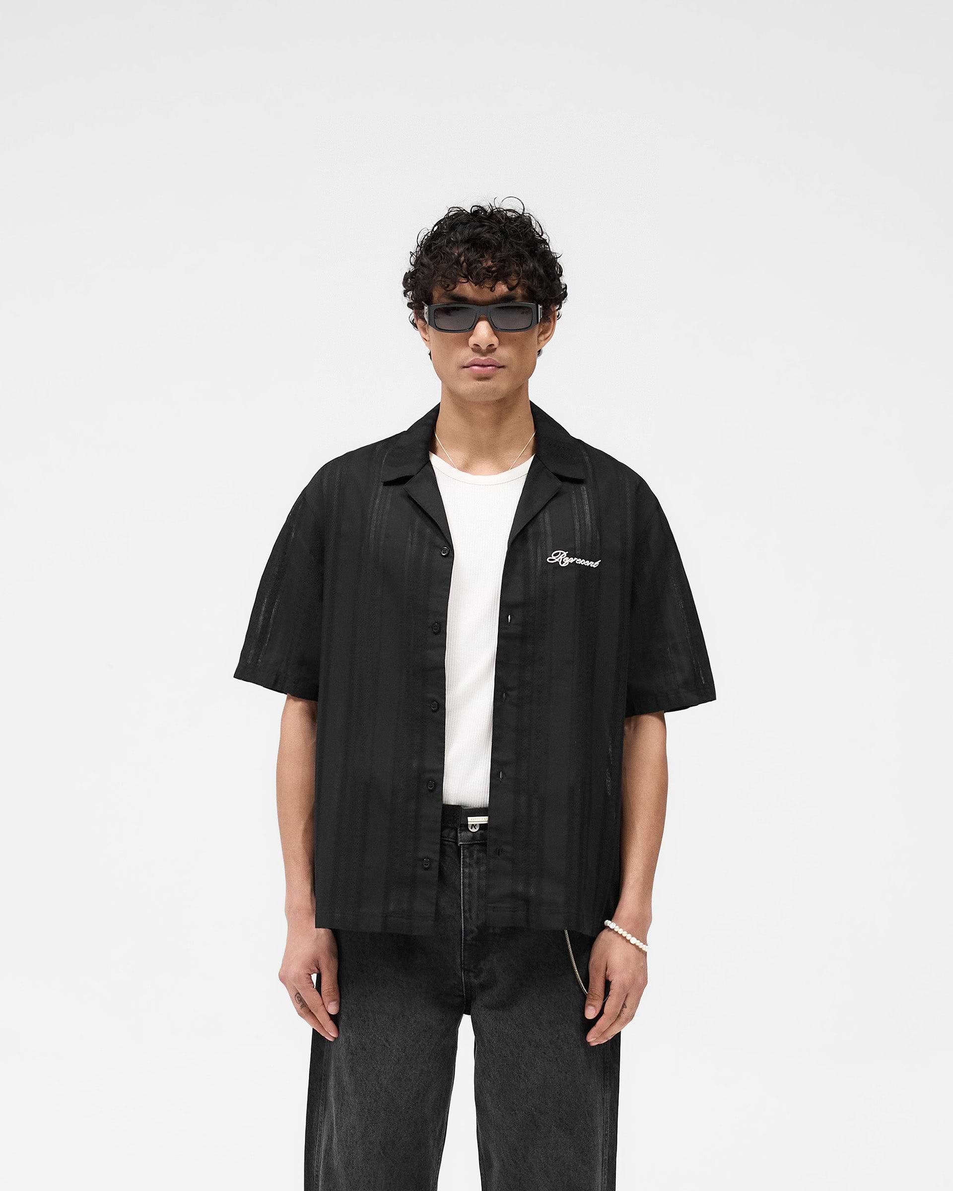 Man wearing a black bowling shirt on a plain white background | Embroidered Bowling Shirt in Jet Black | Sheer fabric shirt with embroidered logo | SS25 Shirts | Represent Clo