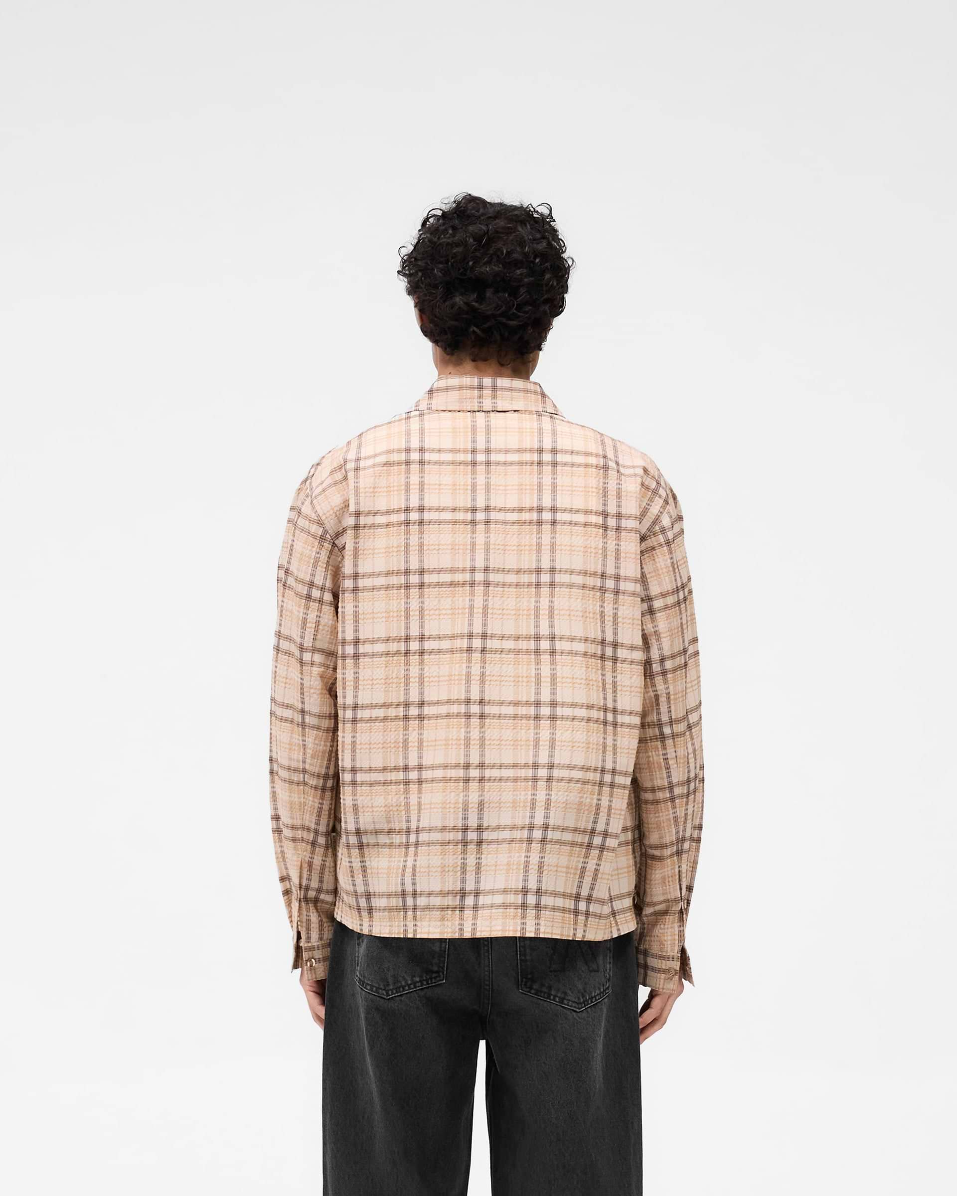 Man wearing a brown check shirt on a plain white background | Sheer Flannel Shirt in Brown Check | Lightweight breathable shirt with button-front closure and chest pockets | SS25 Shirts | Represent Clo