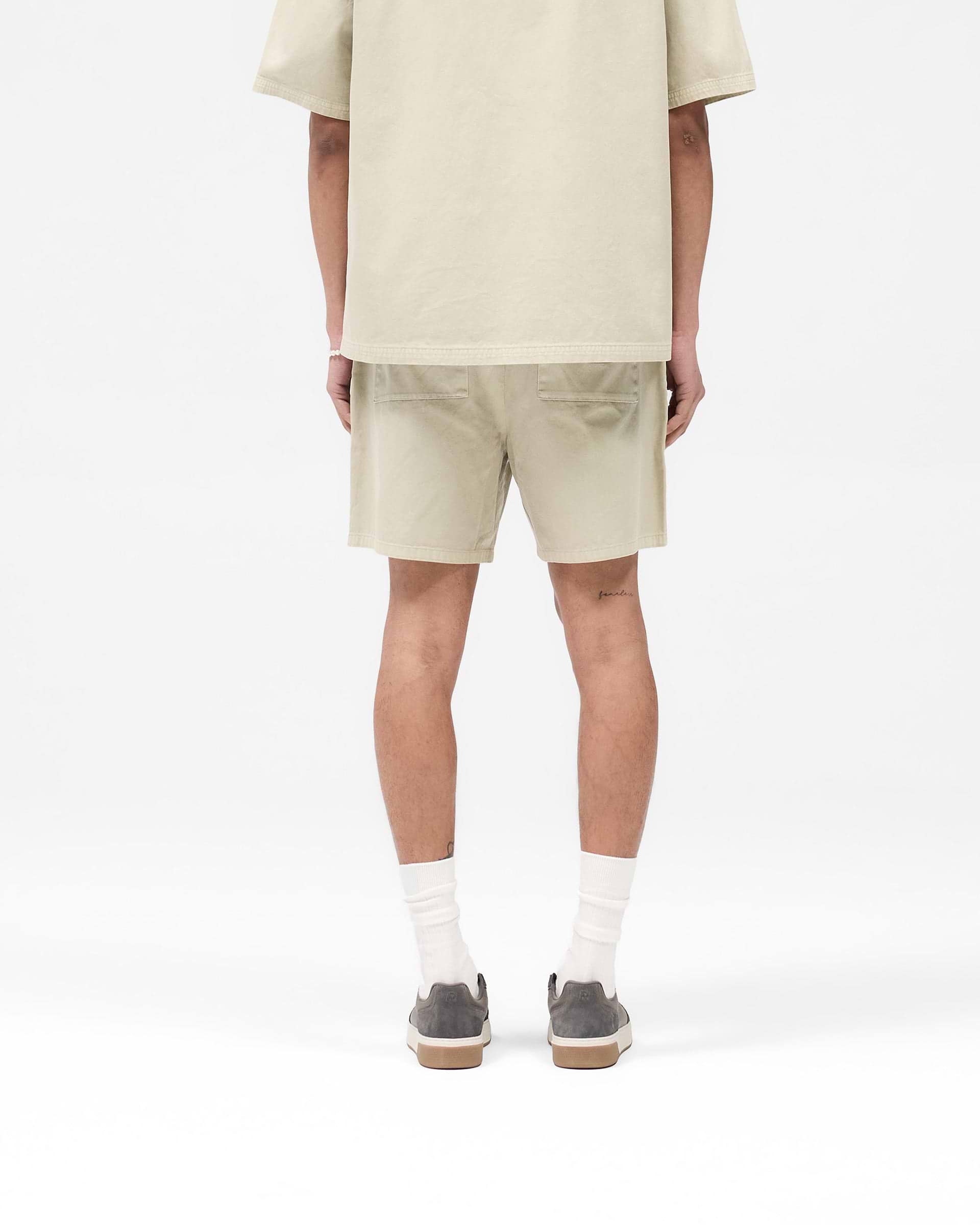 Man wearing beige tailored shorts on a plain white background | Cotton Tailored Short in Beige | Structured fit shorts with side seam pockets | SS25 Shorts | Represent Clo