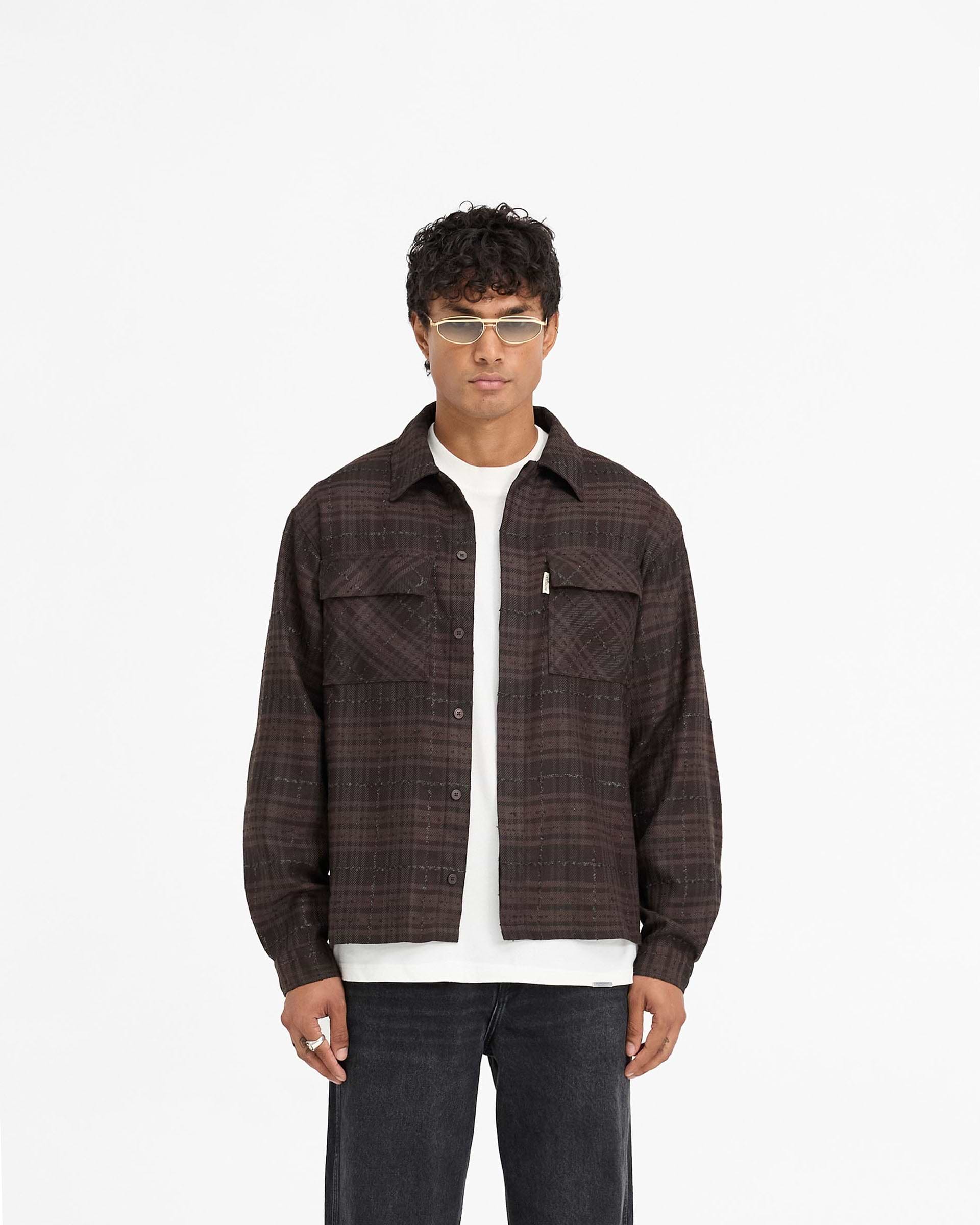 Man wearing a brown flannel shirt on a plain white background | Rep Flannel Shirt in Coffee | Slightly oversized shirt with flap chest pockets | FW24 Shirts | Represent Clo